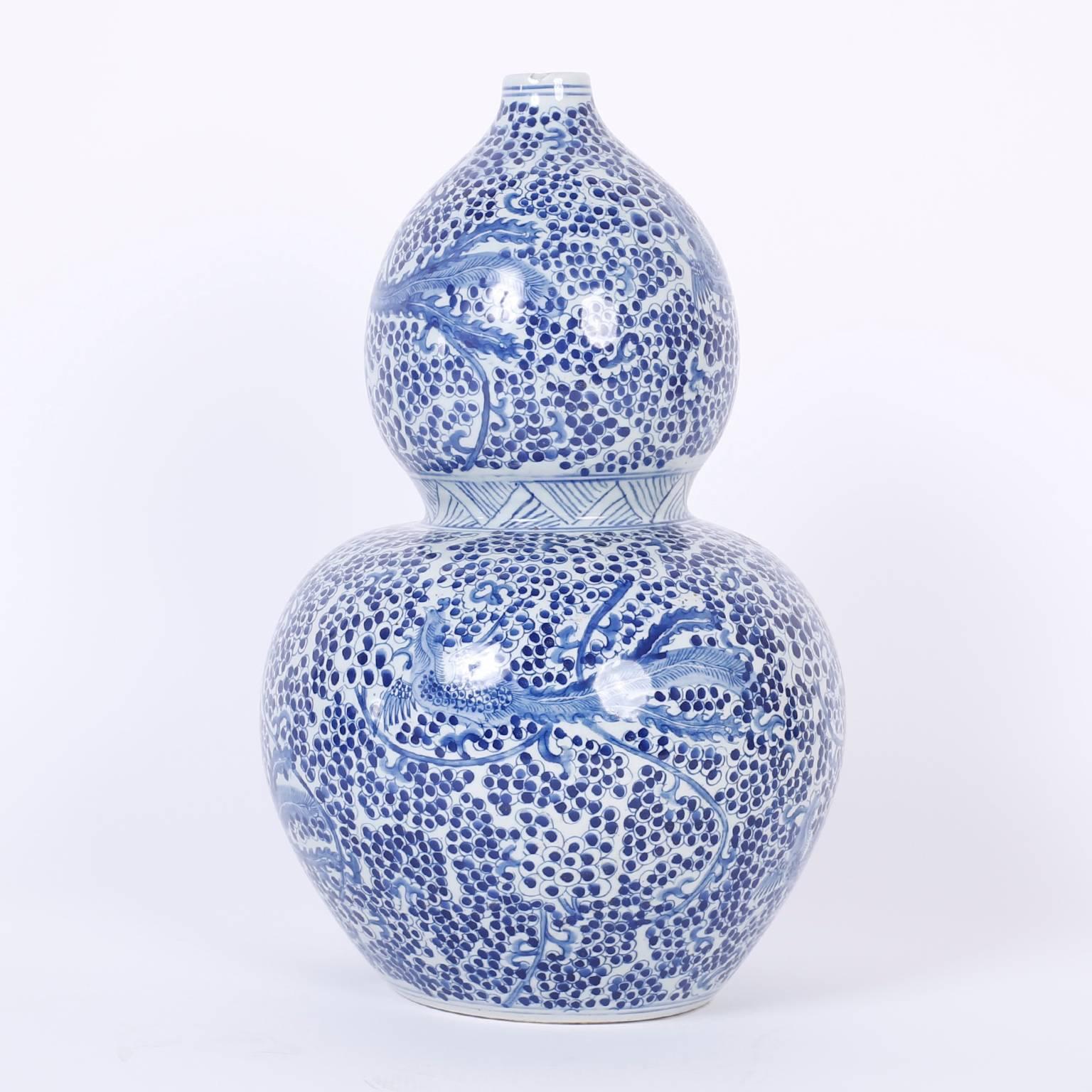 Vogue pair of Chinese blue and white porcelain vases decorated with phoenix birds over a busy field. The hip double gourd form keeps this Classic art form fresh.