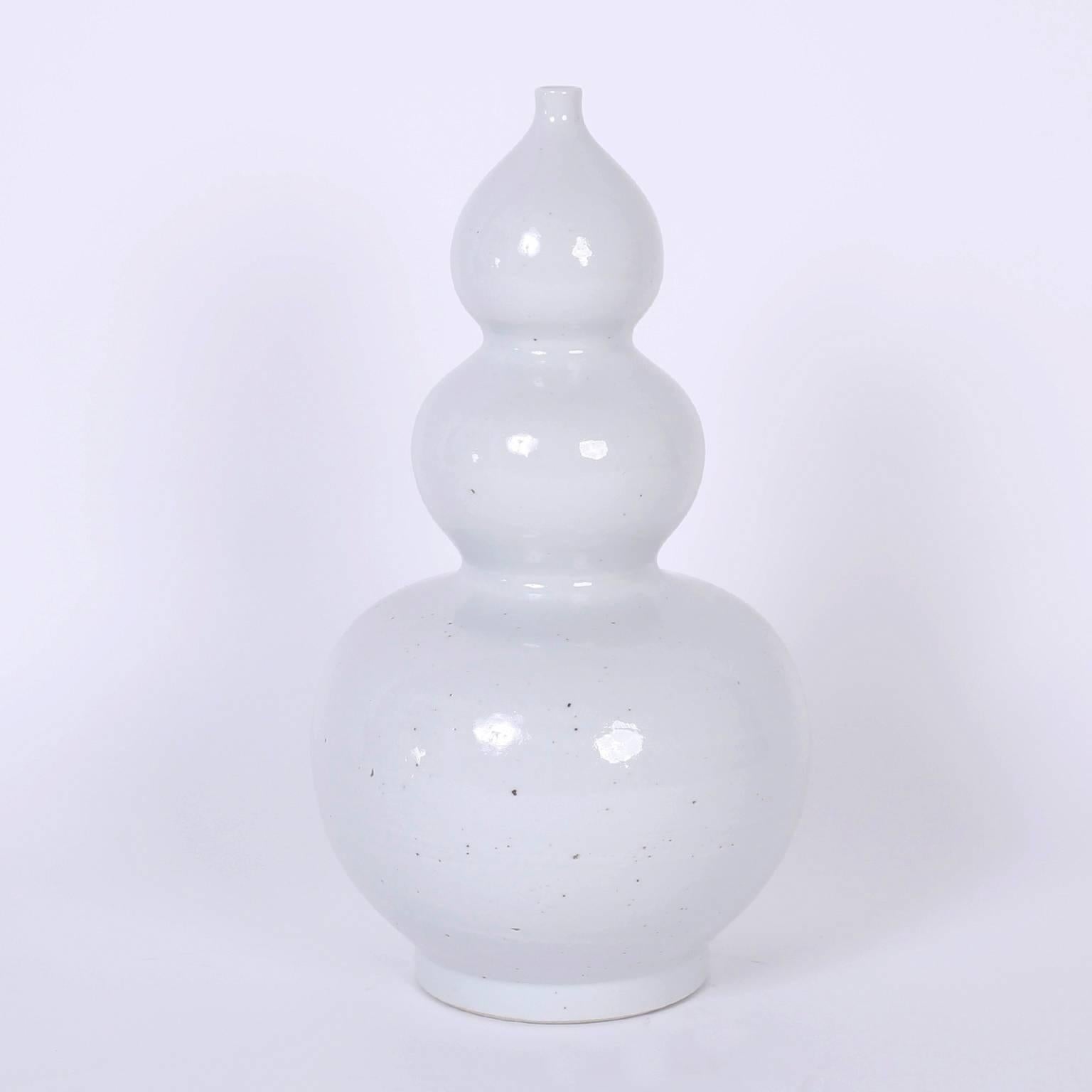 Graceful pair of Chinese porcelain style vases with a pale mellow celadon glaze over a sleek timeless triple gourd form, bridging tradition with modern.