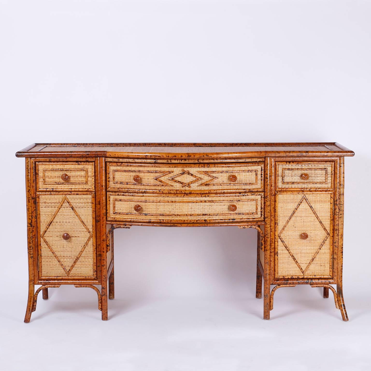 Handsome midcentury British Colonial style credenza or sideboard featuring a faux bamboo and grass cloth facade that gives this bow front serving piece an organic casual elegance.

A rare form in bamboo, this pieces also works well in an Anglo