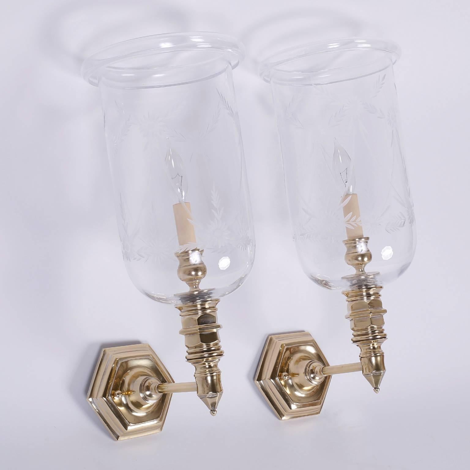 Pair of sconces with handblown glass hurricane shades etched with floral designs. The hand polished and lacquered back plates and arms have influences from Queen Anne to the Victorians.