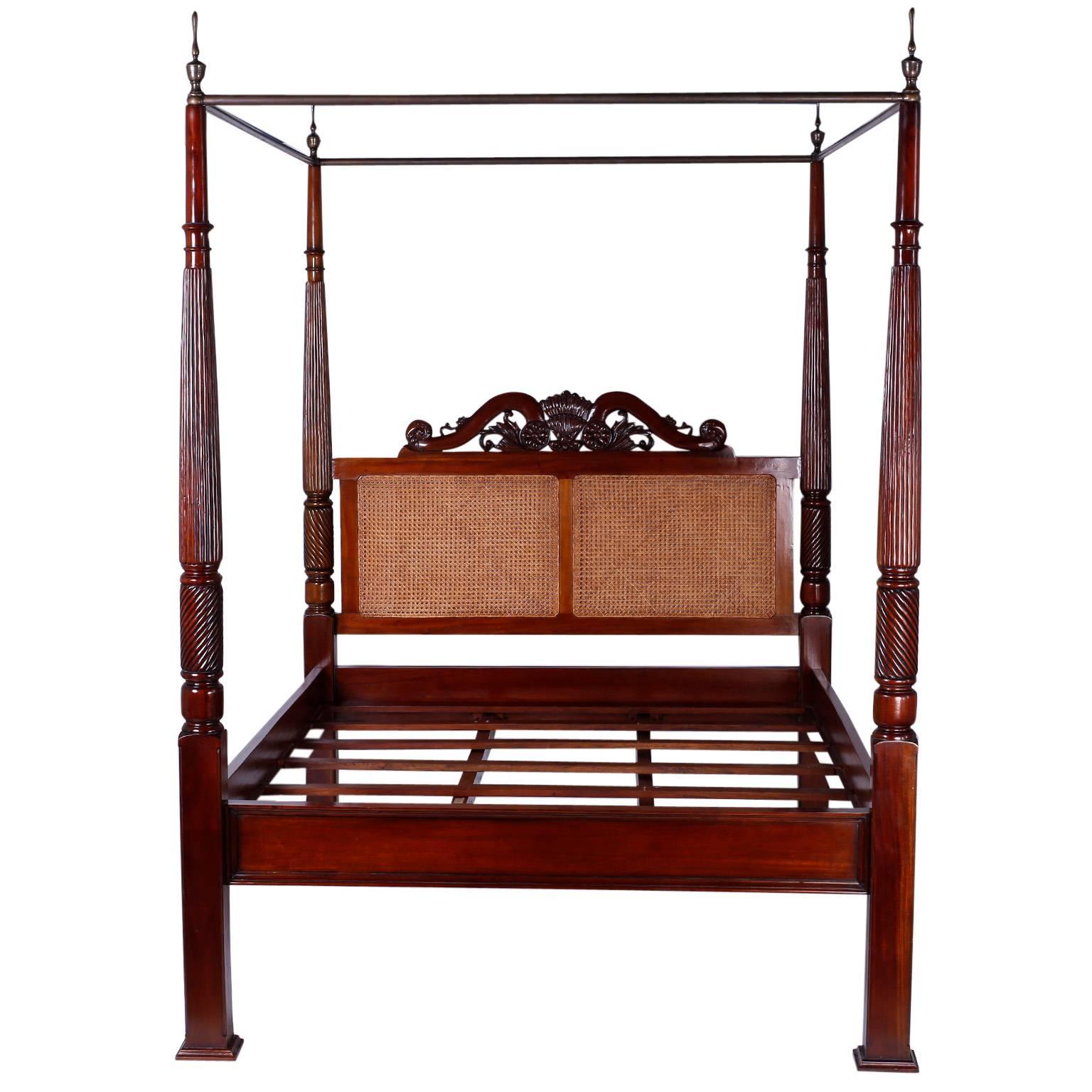 West Indies British colonial style queen-size canopy bed crafted with indigenous mahogany and featuring a double panel caned headboard crowned with a wood carving depicting sea shells and ocean waves. The four posts are turned and beaded while