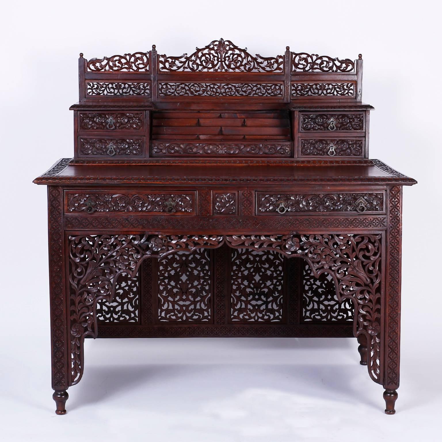 Anglo Indian desk with the unmistakable air of importance. Expertly crafted in bombay blackwood, a rare indigenous hardwood, and ambitiously carved with open floral fret work that breathes in a tropical climate. Having six drawers and a letter