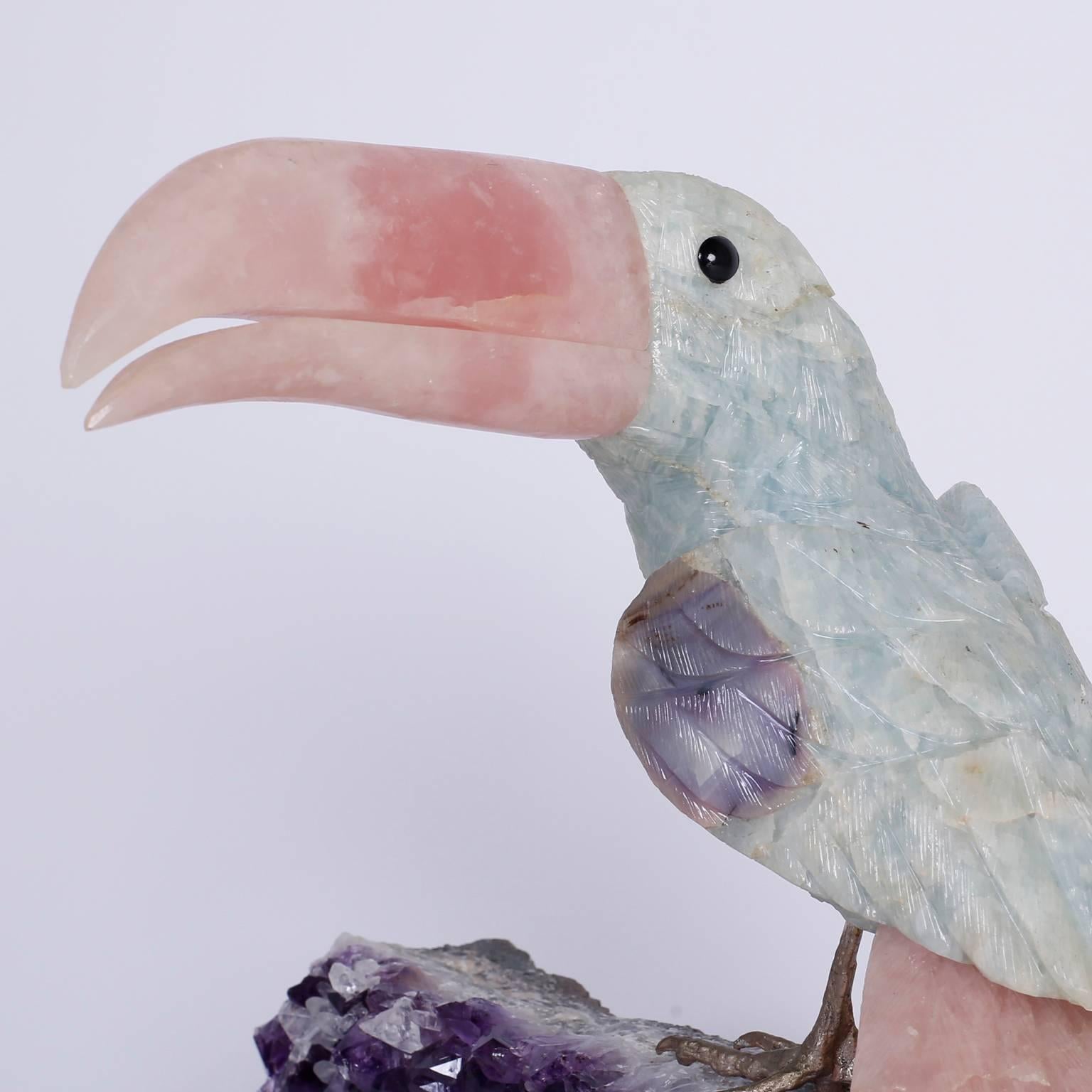Stone toucan carved from quartz with its iconic profile and amusing personality set on brass feet perched on an amethyst geode specimen.