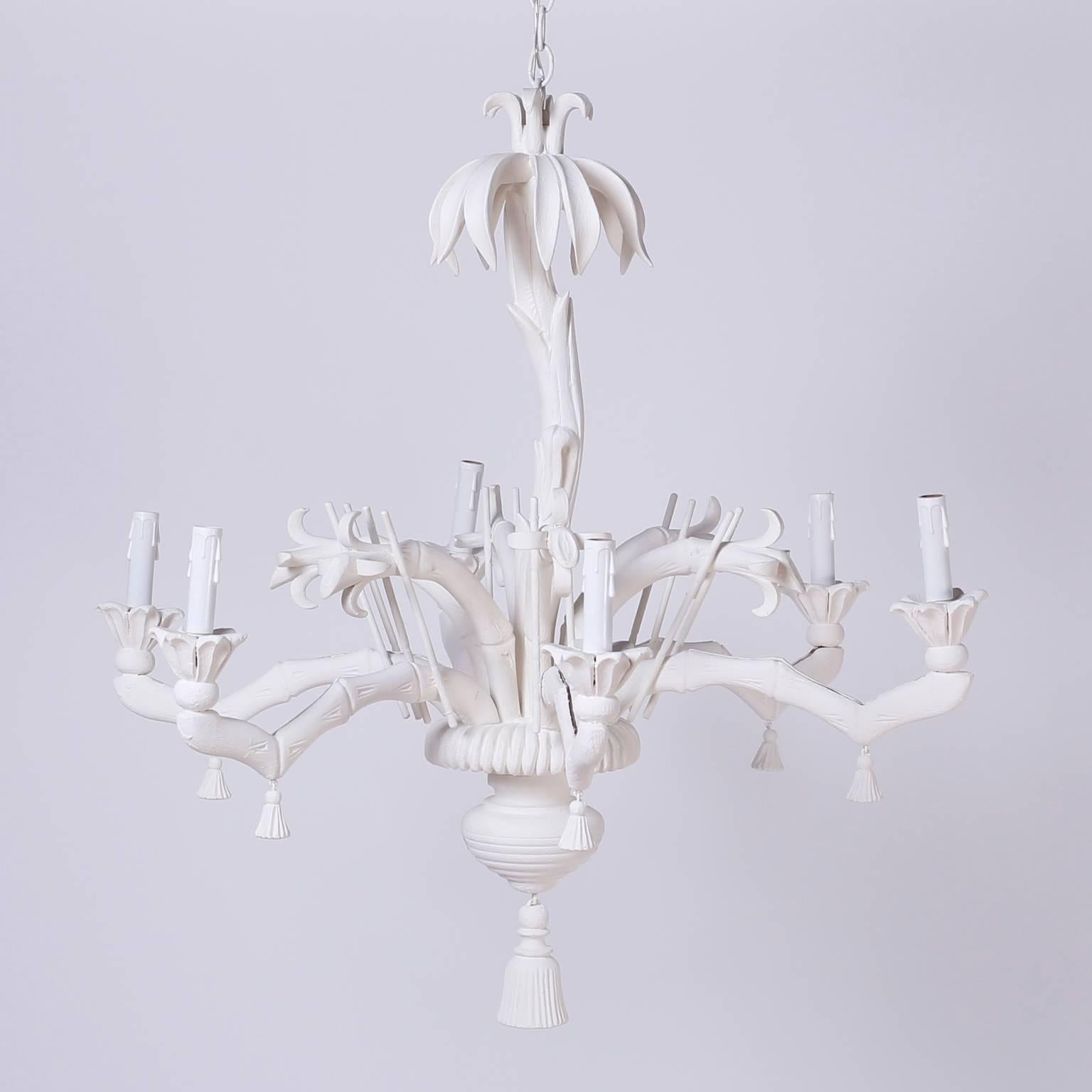Mid century Italian chandelier with a light hearted whimsical chinoiserie form, constructed with carved wood and white lacquer. Having a palm tree trunk, flowers, stems, and six stylized faux bamboo arms with dangling tassels. This light fixture
