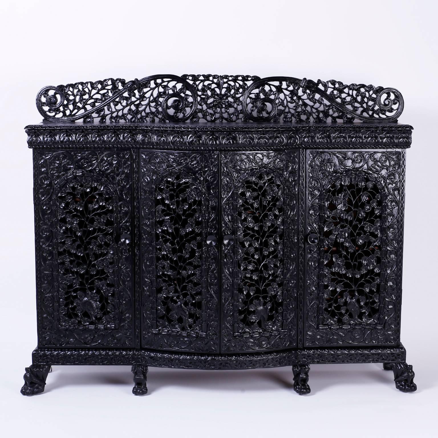 Anglo Indian cabinet or credenza intricately carved with dramatic floral designs throughout. Featuring a bold backsplash, open fret work on all four doors with six animal paw feet offering plenty of storage and a strong presence.