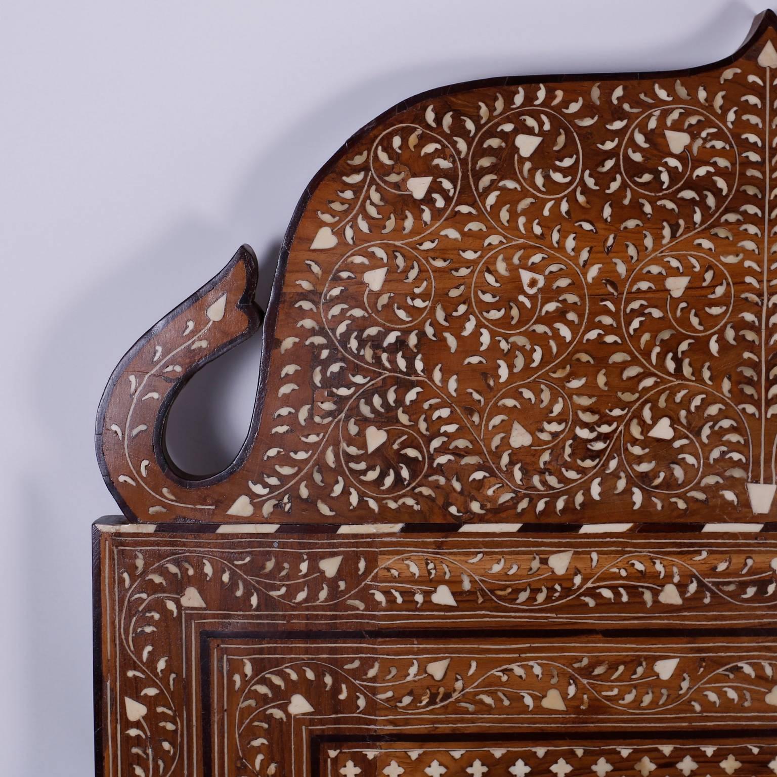 Anglo-Indian or Syrian exotic wall mirror with a walnut frame having intricate floral and geometric inlays. Featuring a bone inlaid walnut crown depicting the form of two charming elephants with their trunks up for good luck.
 