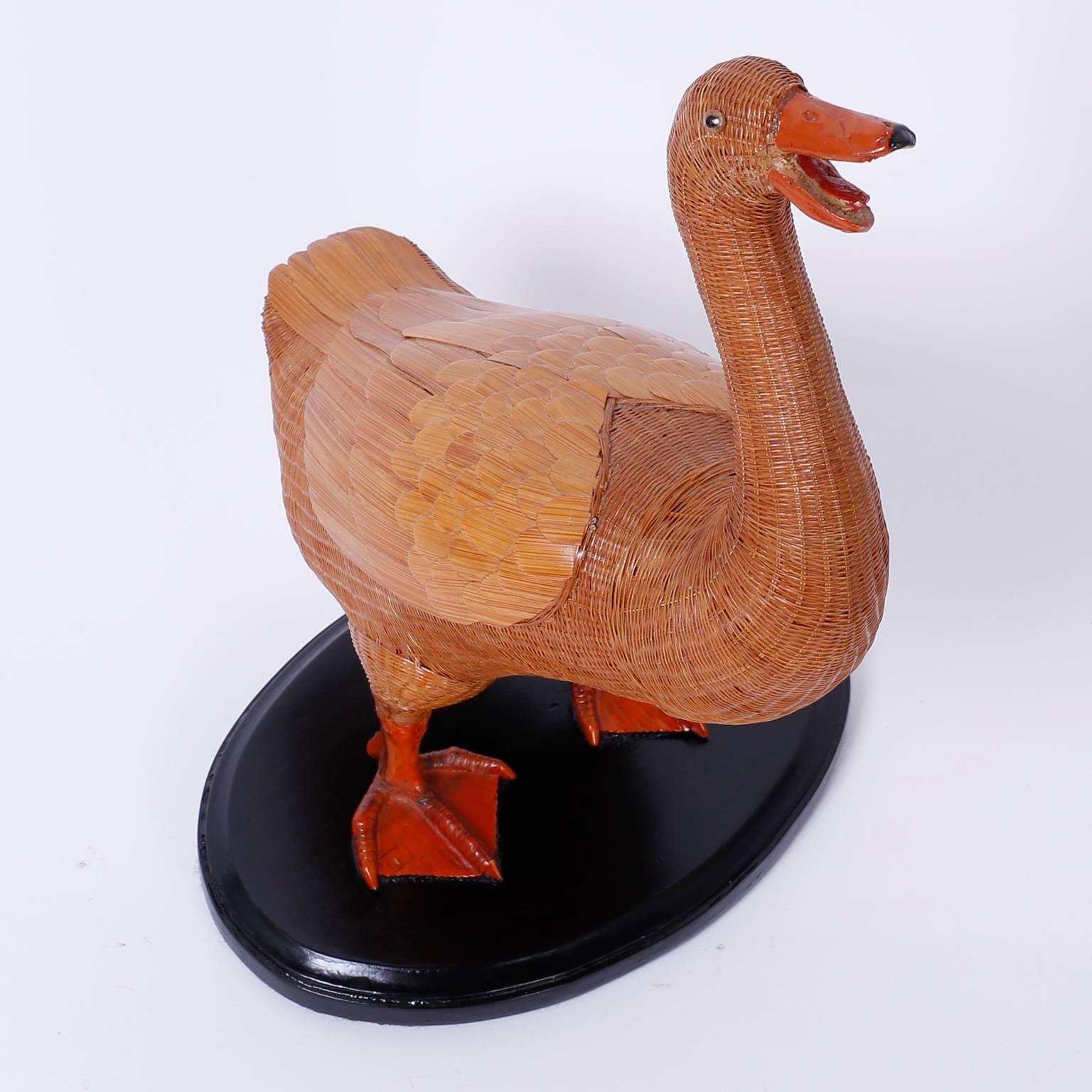 Wicker duck from with an intricate woven wicker structure and highlighted with wood wings and a sculpted bill and feet. Presented on a lacquered wood base.  
 