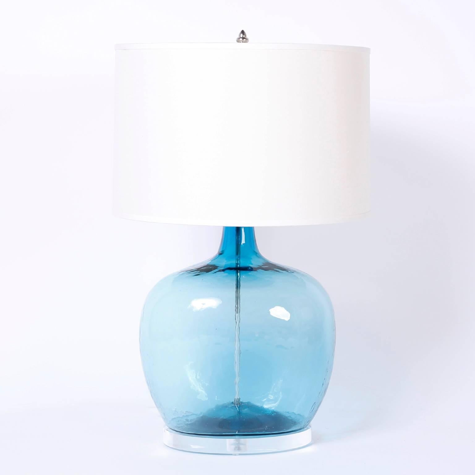 Pair of table lamps custom designed and made by F.S. Henemader. Created with alluring handblown blue glass bottles on Lucite stands.
