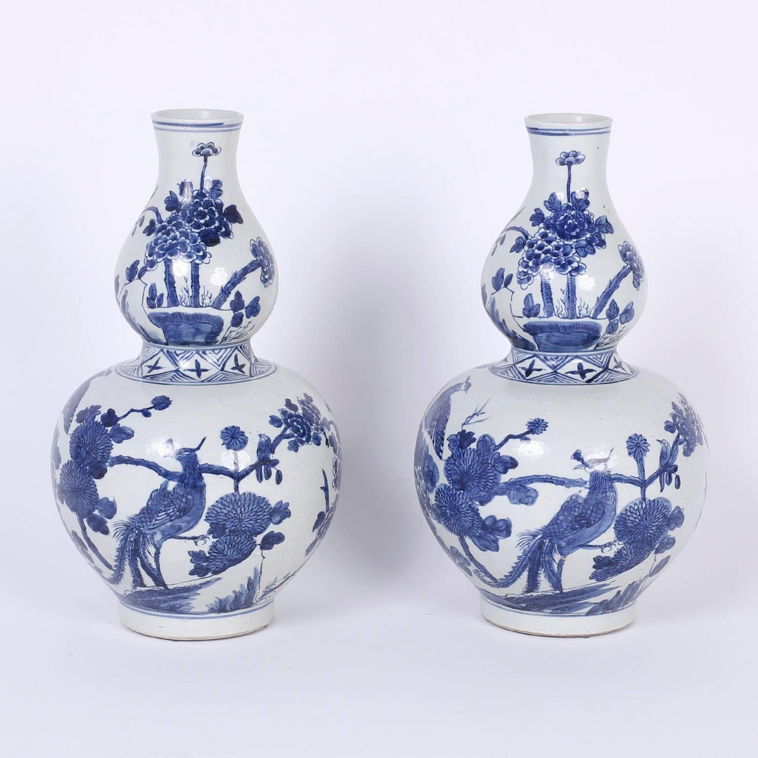 Pair of blue and white Chinese porcelain vases with classic double gourd form and hand decorated fauna and flora depicting quails and peonies.