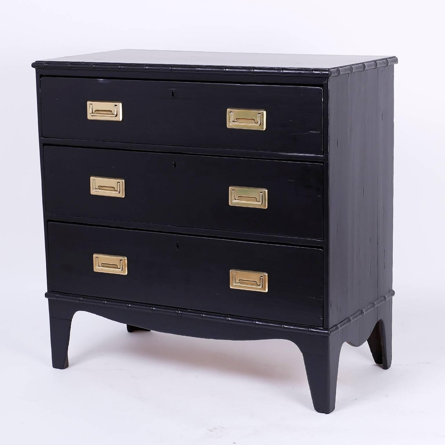 A three-drawer chest of drawers, with an ebonized finish, faux bamboo trim, and high bracket base and recessed Campaign style brass hardware. A great size, and a real looker.

 