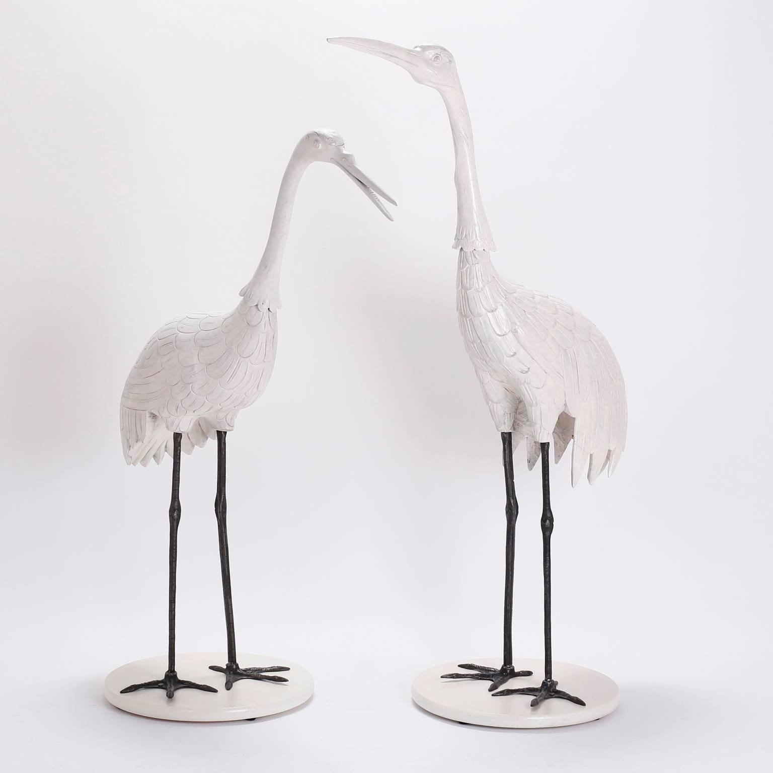Chic, mid century pair of crane or stork sculptures crafted in carved wood with a custom lacquered finish. The legs are raw iron ,sealed for easy care, presented on round lacquered wood bases. 

From left to right:

H: 50 W: 42 D: 18
H: 56 W: 38 D: