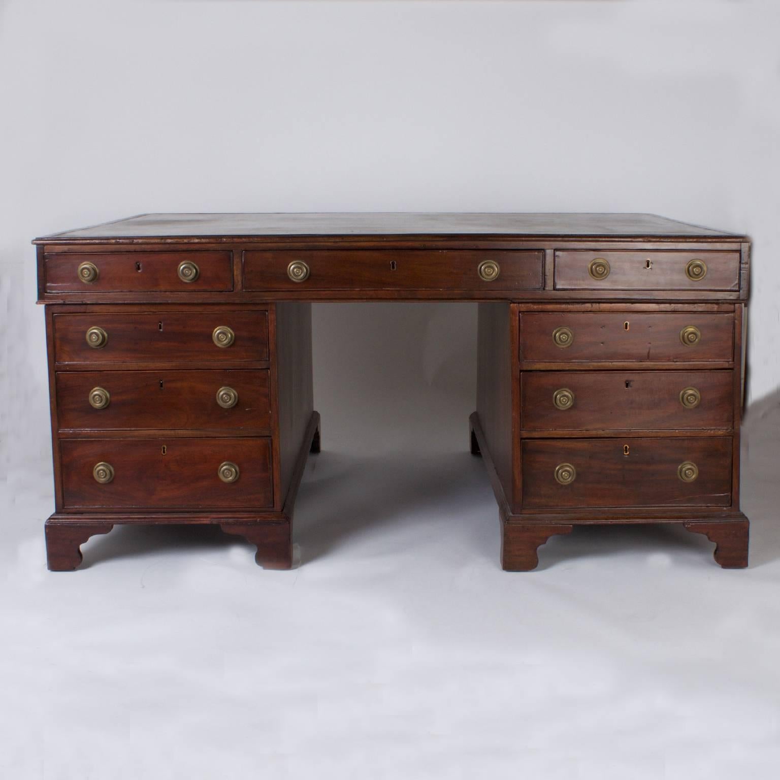 Large-scale, 19th century three part English mahogany partners desk, executed in a Georgian style and featuring a mossy green, tooled leather top with warm, aged patina. Nine drawers on each side, brass hardware and all settled on an outside bracket