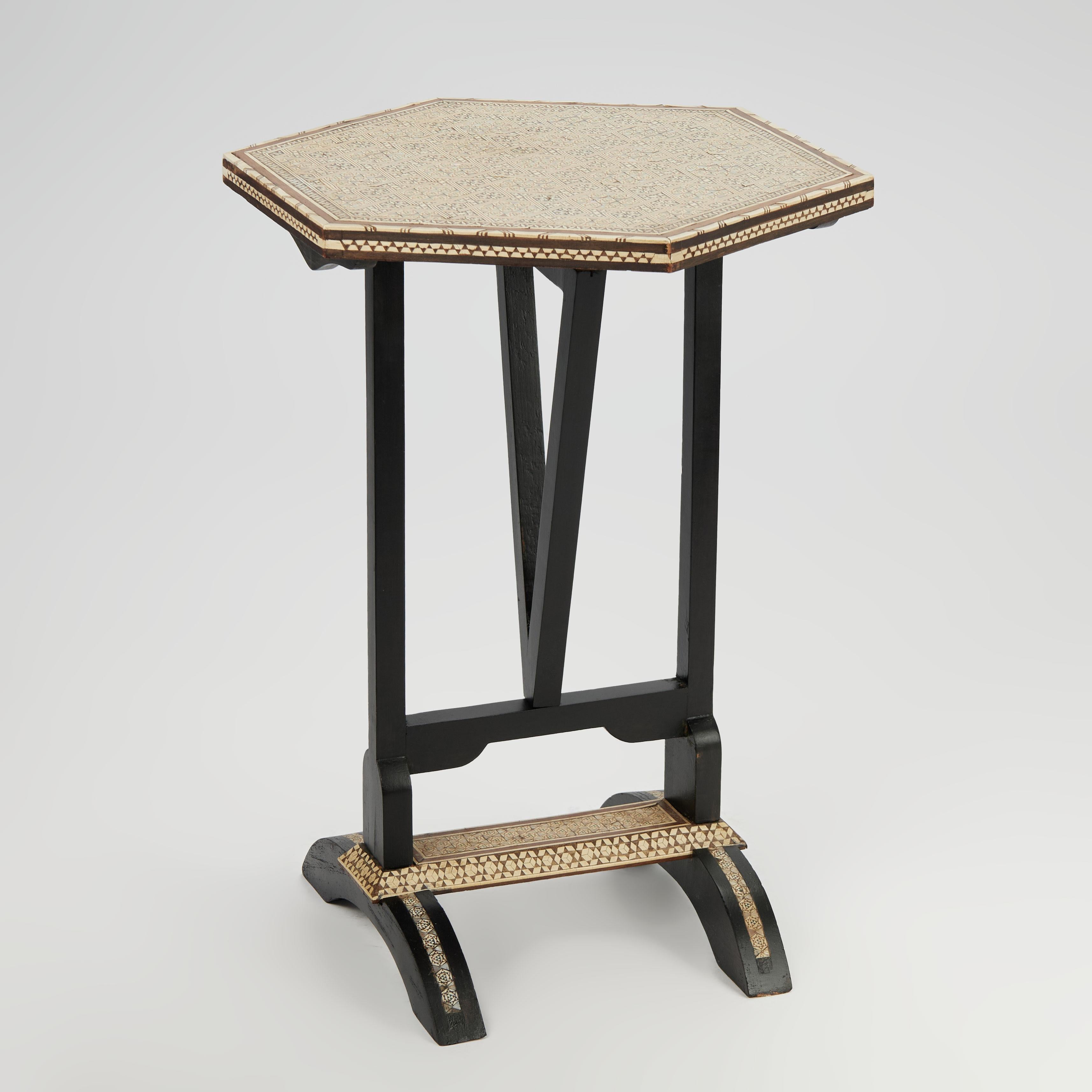 Lofty vintage Moroccan stand crafted in indigenous hardwoods with a hexagon tilt top featuring mother of pearl, bone, ebony and walnut inlaid marquetry on an ebonized base with a swivel brace on inlaid marquetry legs.