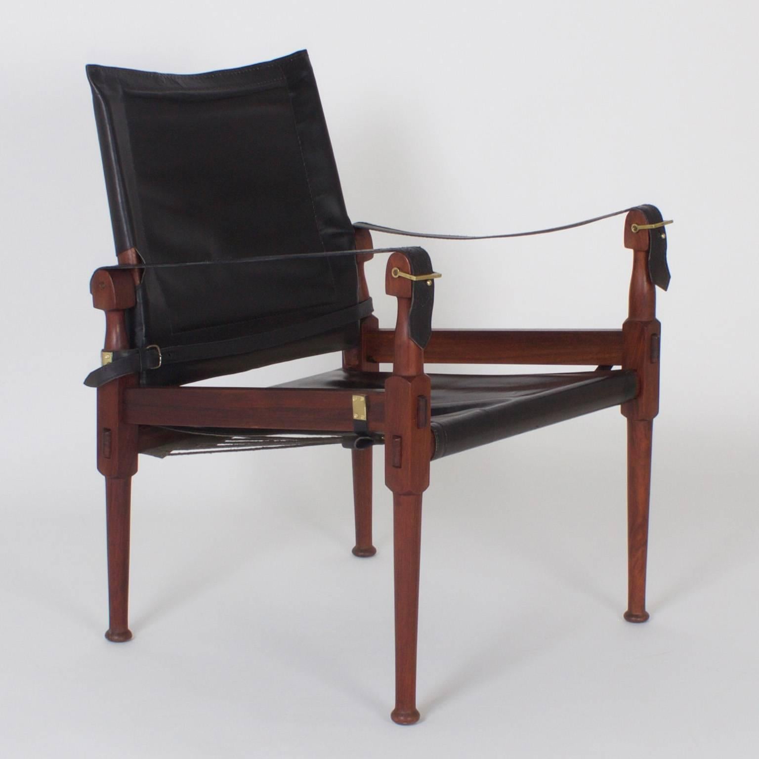 A rare set of four Safari or Campaign chairs with an easy, relaxed design. Crafted in the Mid-Century in Pakistan from rosewood. The sling style arms, seat and adjustable back are luxurious, soft black leather. All four chairs signed 