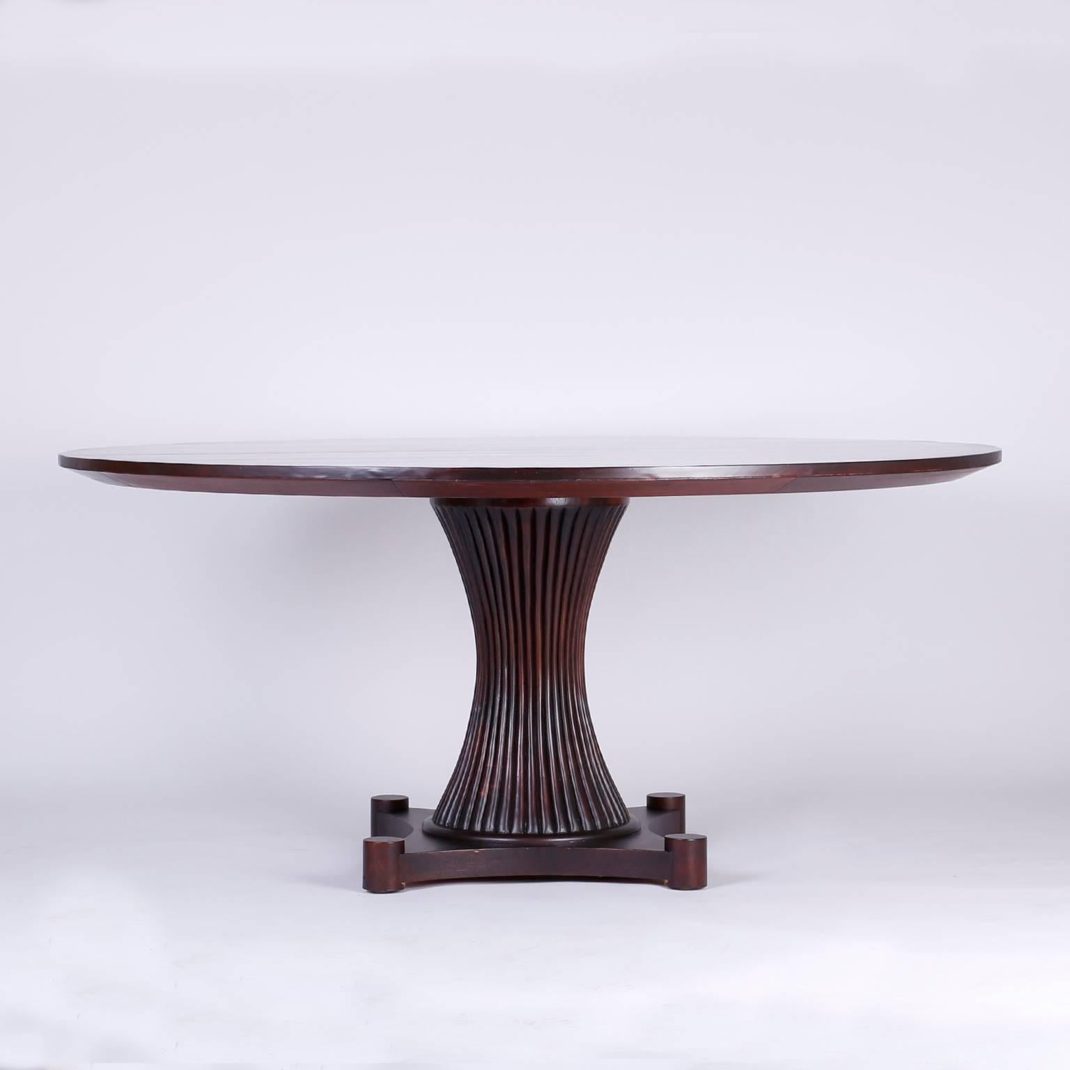 Sleek, midcentury mahogany table with a round top supported by a beaded hour glass shaped base over a stylized Stand on four disk feet. Signed Baker on a silver label.