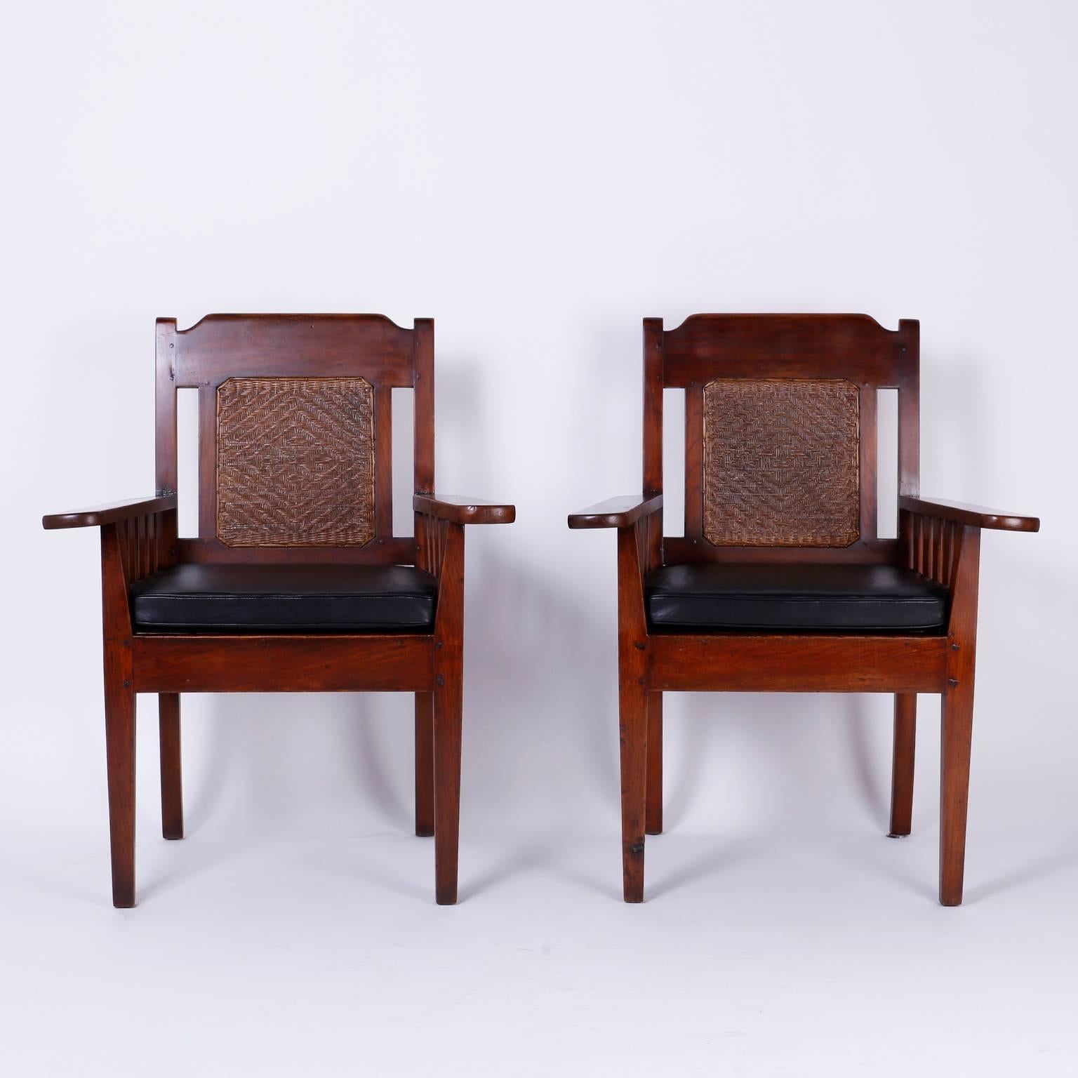 Here is an intriguing pair of Anglo Indian mahogany arm chairs with a curious set of influences. Featuring Herringbone caning on the backs, elongated arms with an arts and Craft or Mission form and pegged construction a seat option of leather