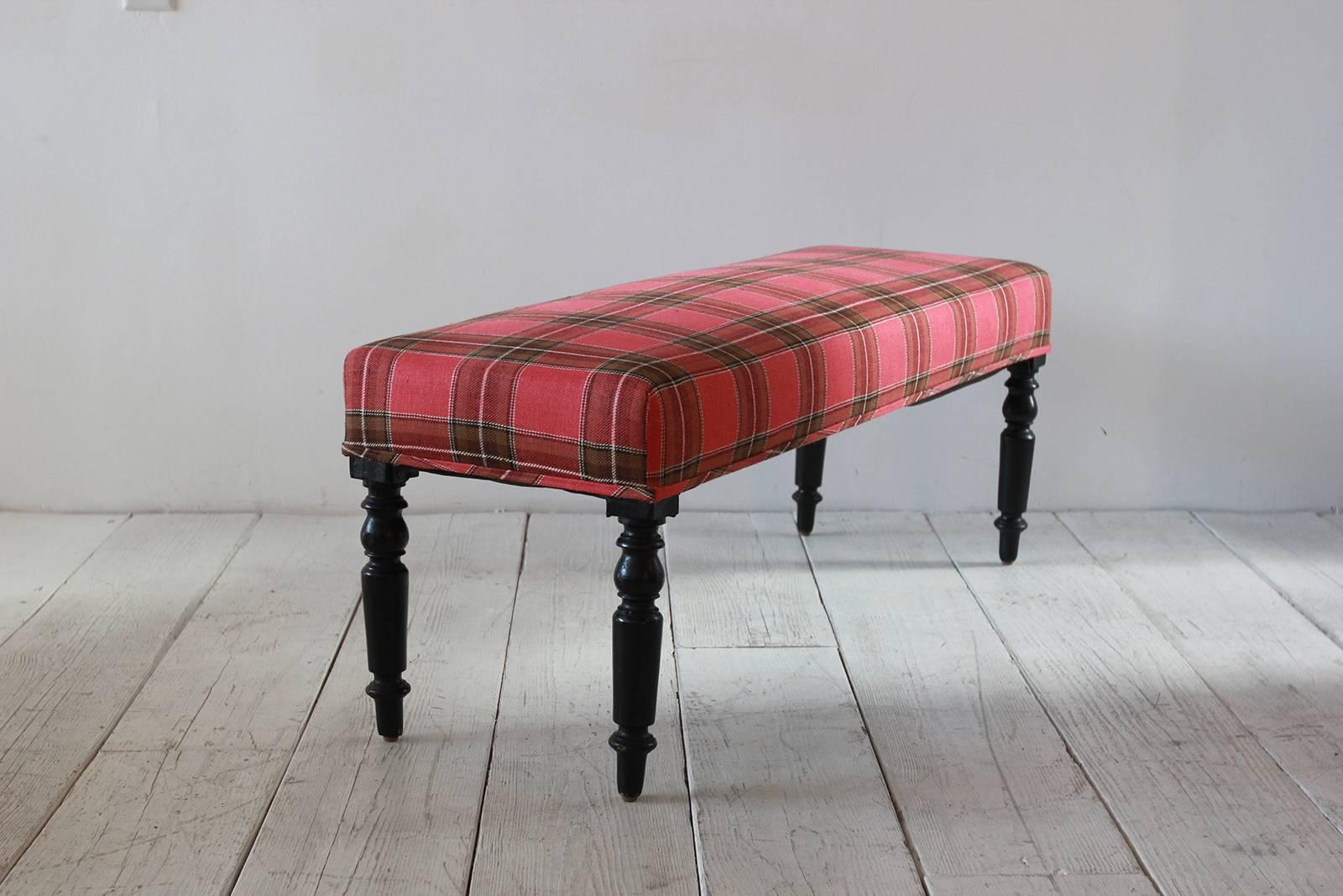Vintage bench with mahogany turned legs newly upholstered in red plaid fabric.