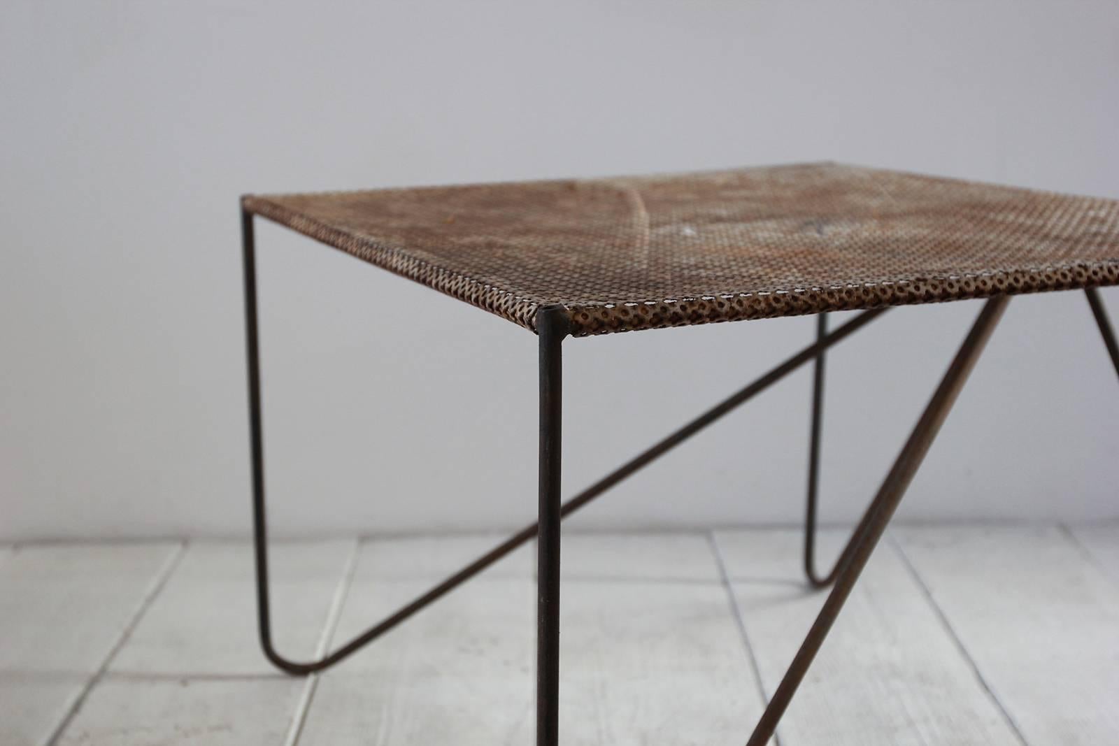 Rustic indoor or outdoor perforated metal side table with angled legs.