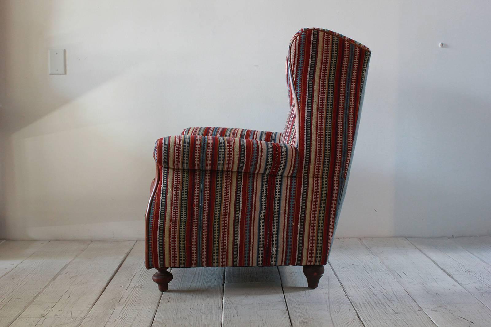 Italian Kilim wing back chair with original leather seat with reverse denim upholstered on the back with turned feet.