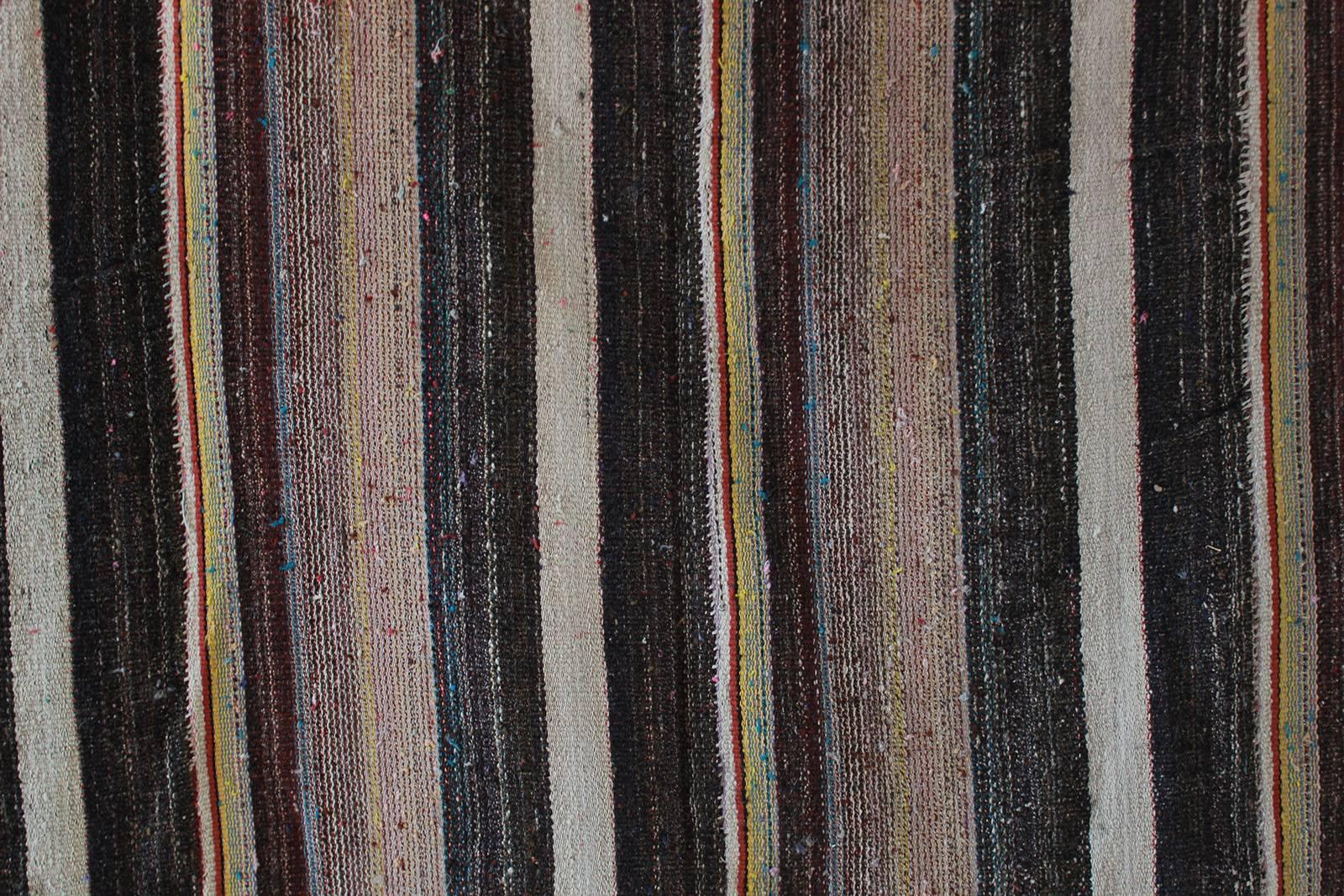 Rustic flat-woven wool striped rug with brown and pink hues.