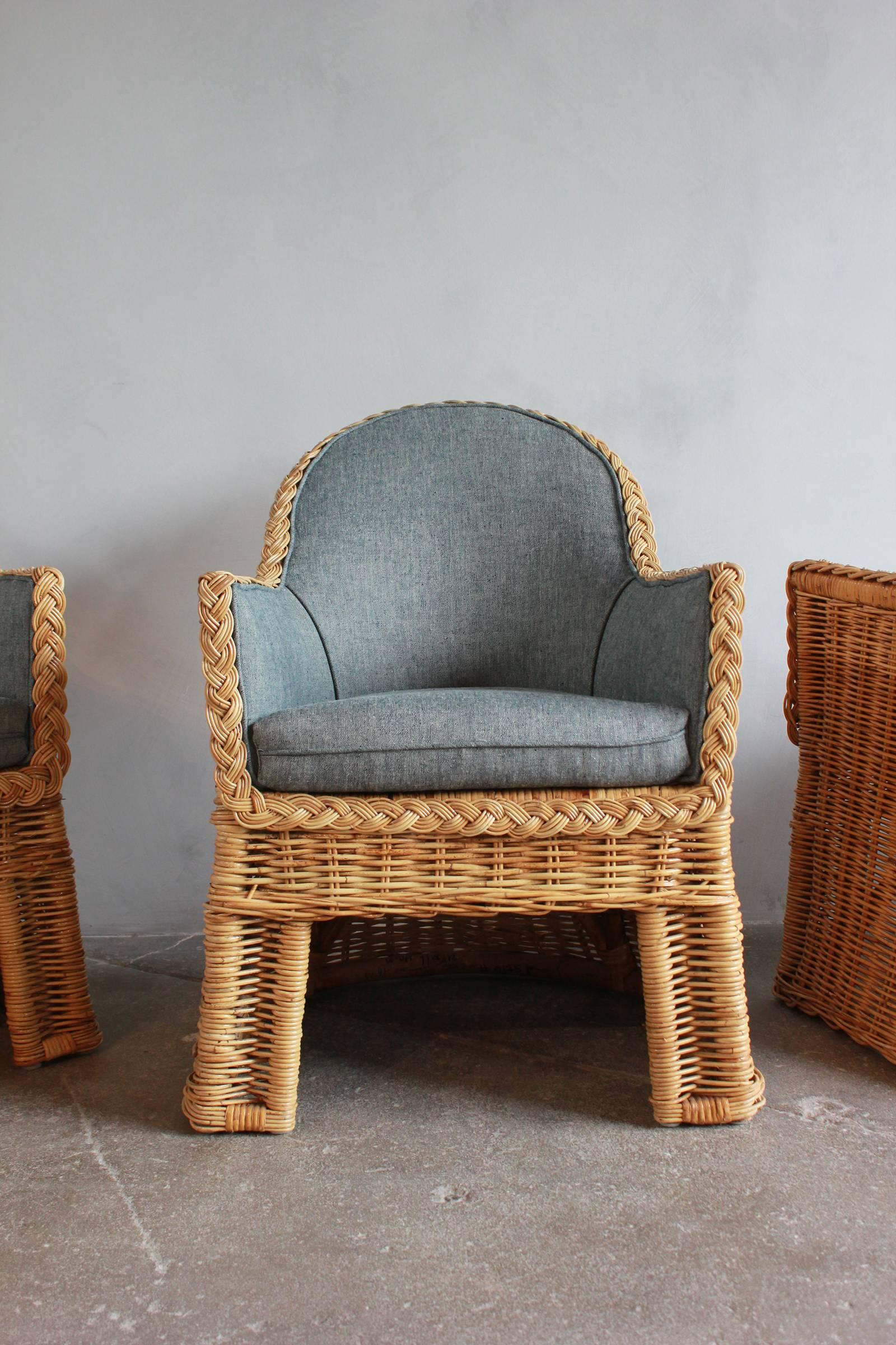 Set of four oversized wicker dining chairs upholstered in reverse denim.