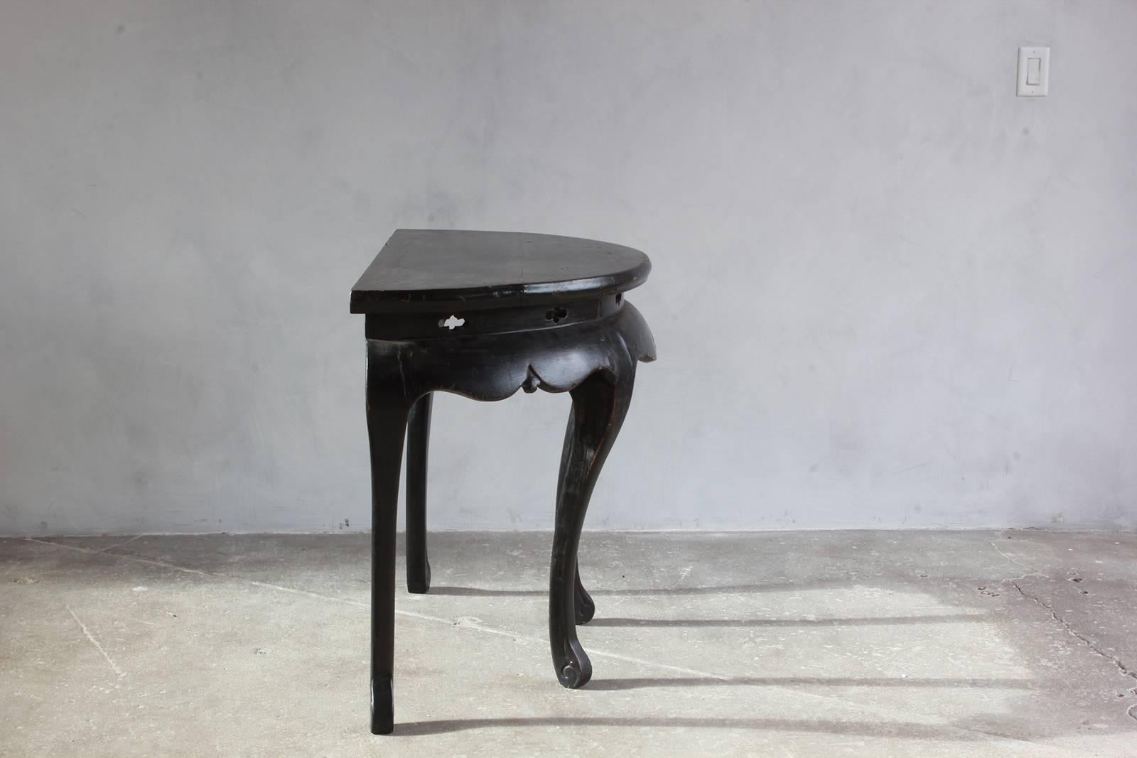 Black lacquered British four-legged demilune with clover cut-out details.