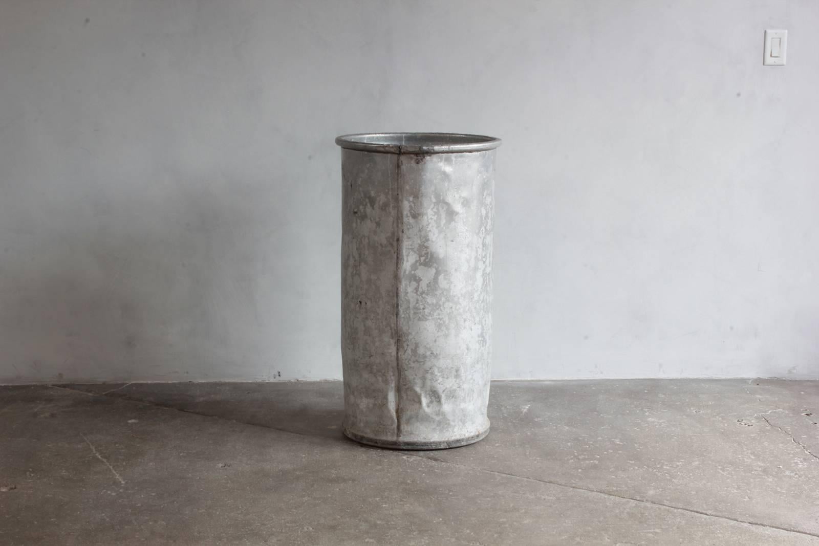 Tall galvanized cylindrical bin.
