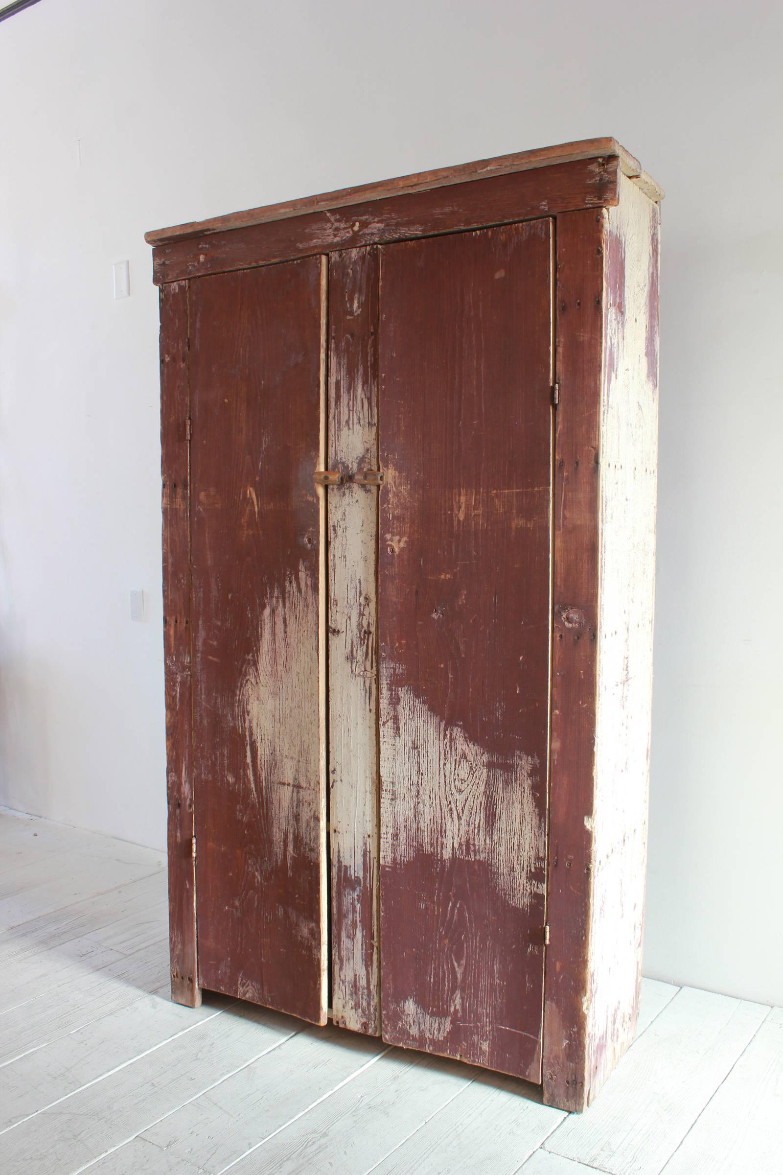 Tall rustic two door painted cabinet with interior shelves.