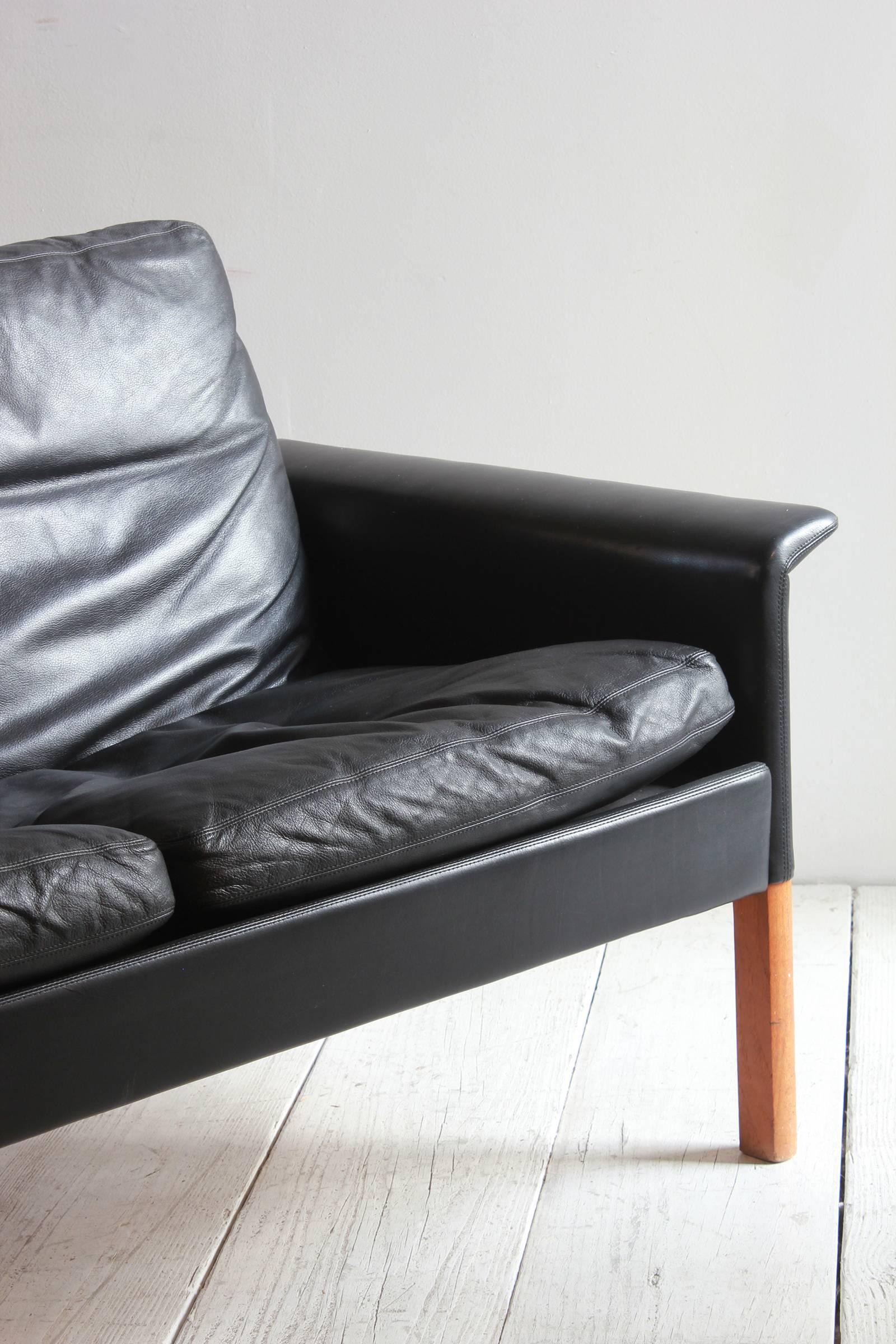 Hans Olsen style black leather sofa with six loose cushions.