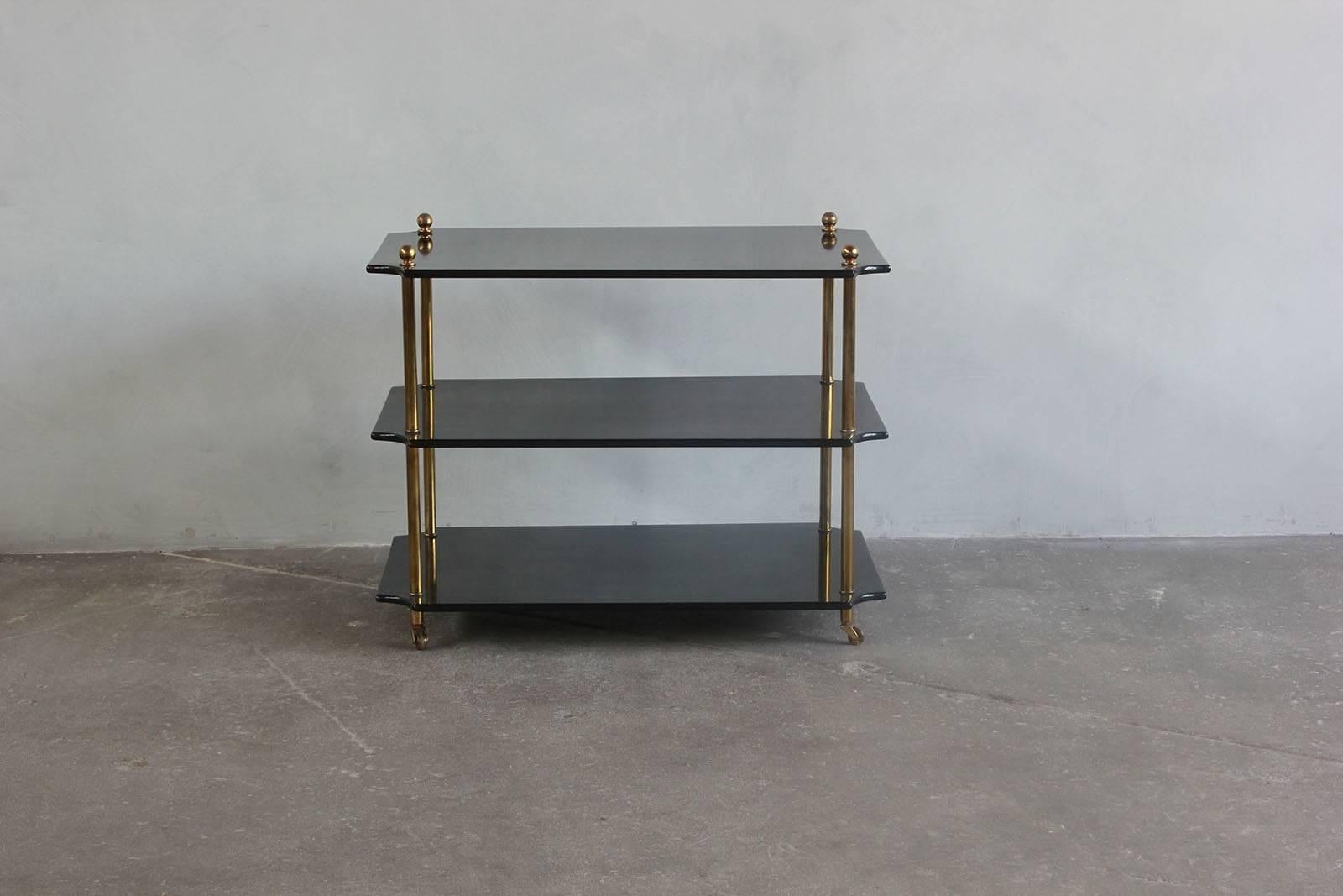 Pair of black lacquered three-tiered side tables with brass details and casters.