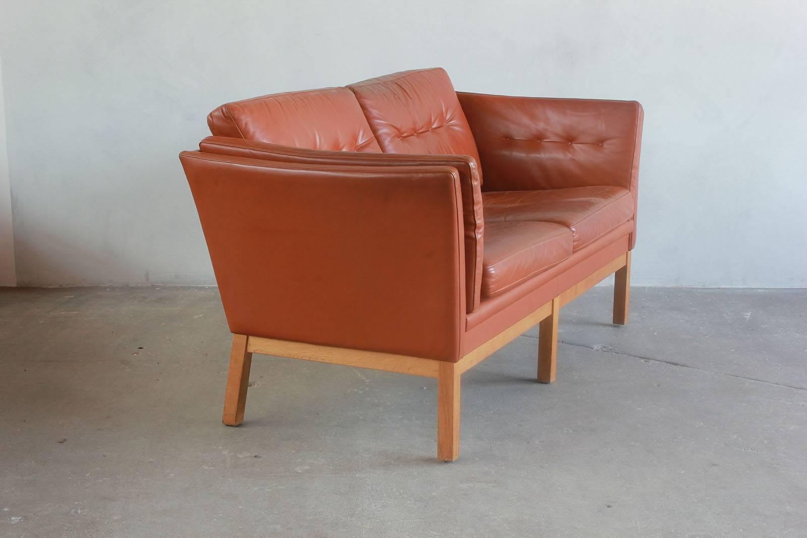 Danish leather two-seat settee with oak frame.