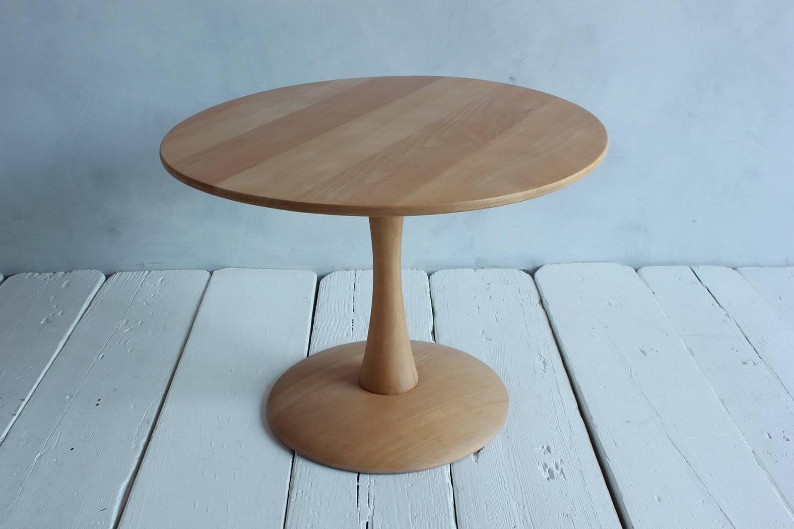 Round low oak side table on a tulip pedestal base.