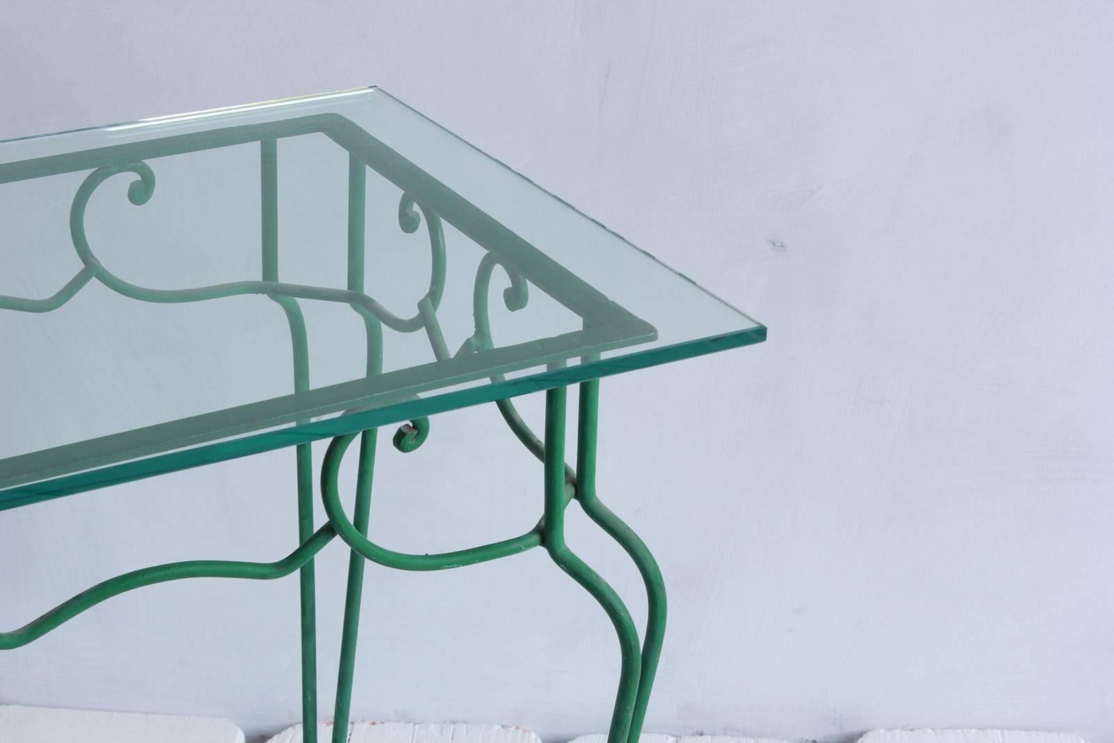 Green metal scrolled side table with glass top.