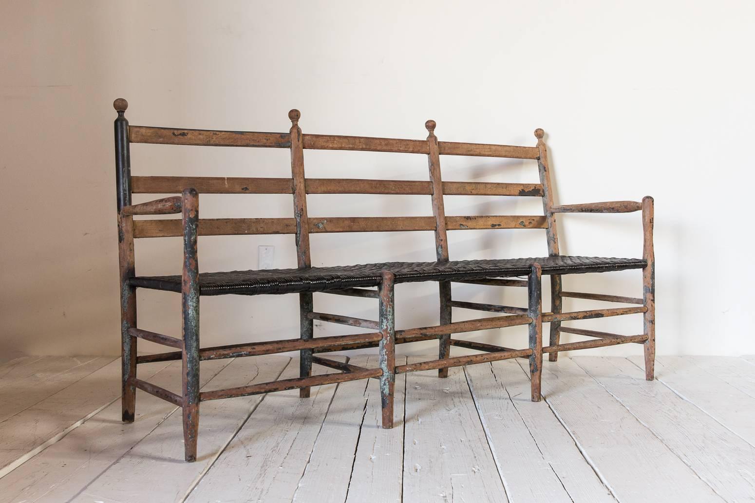 Rustic ladder back bench with spindle details and black rush seat.