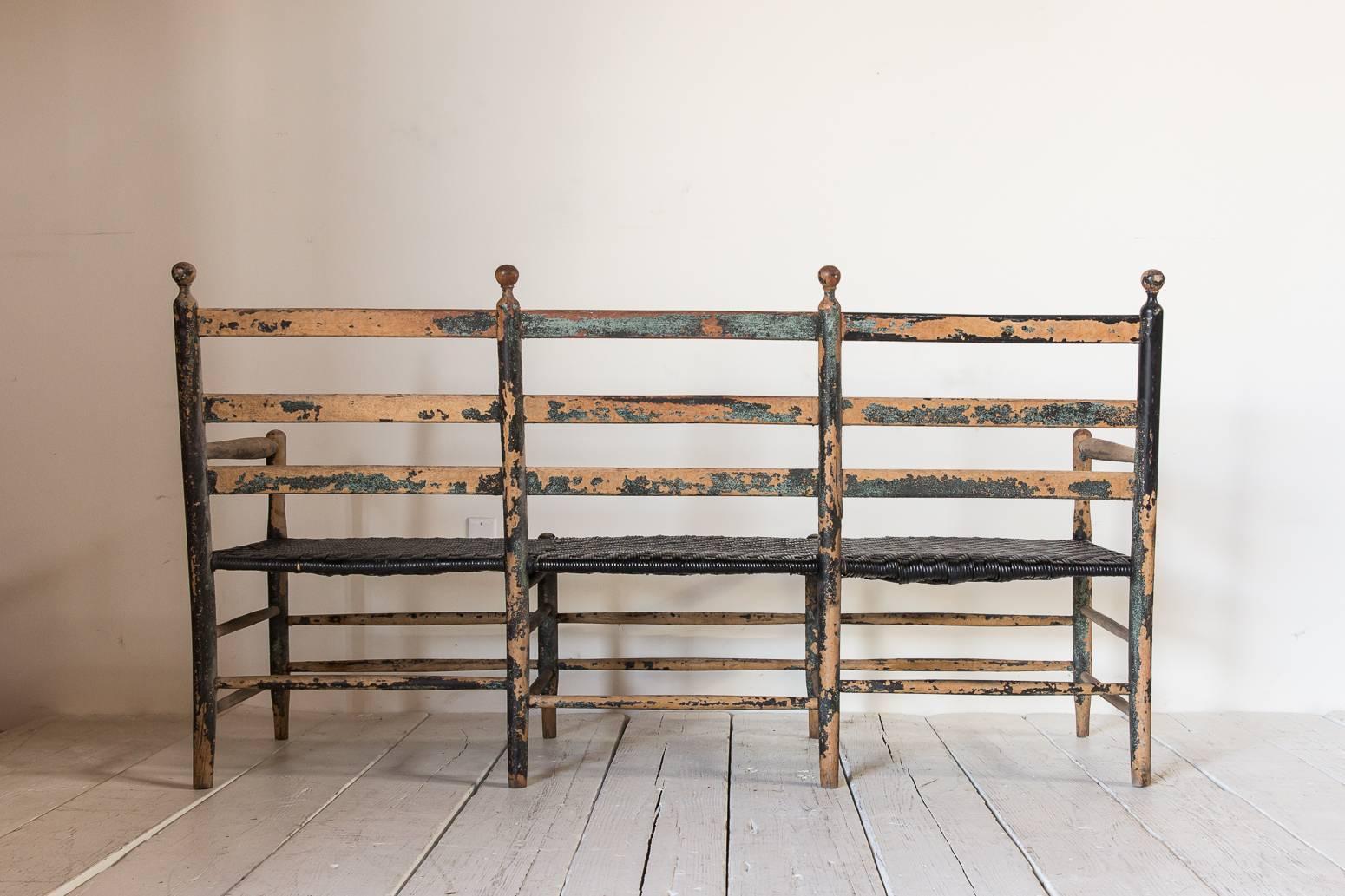 Rustic Ladder Back Bench with Spindle Details and Black Rush Seat In Distressed Condition In Los Angeles, CA