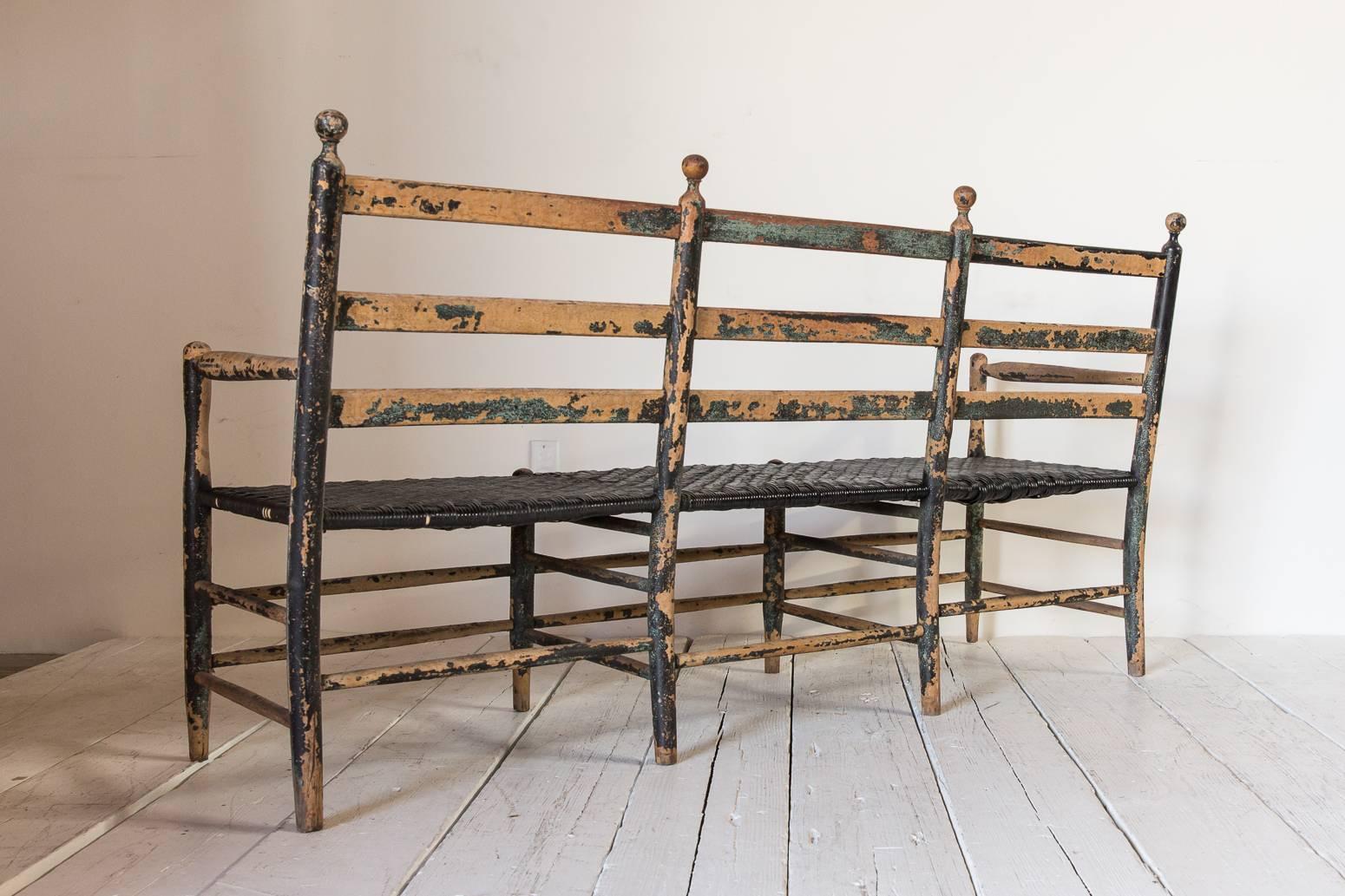 Early 20th Century Rustic Ladder Back Bench with Spindle Details and Black Rush Seat