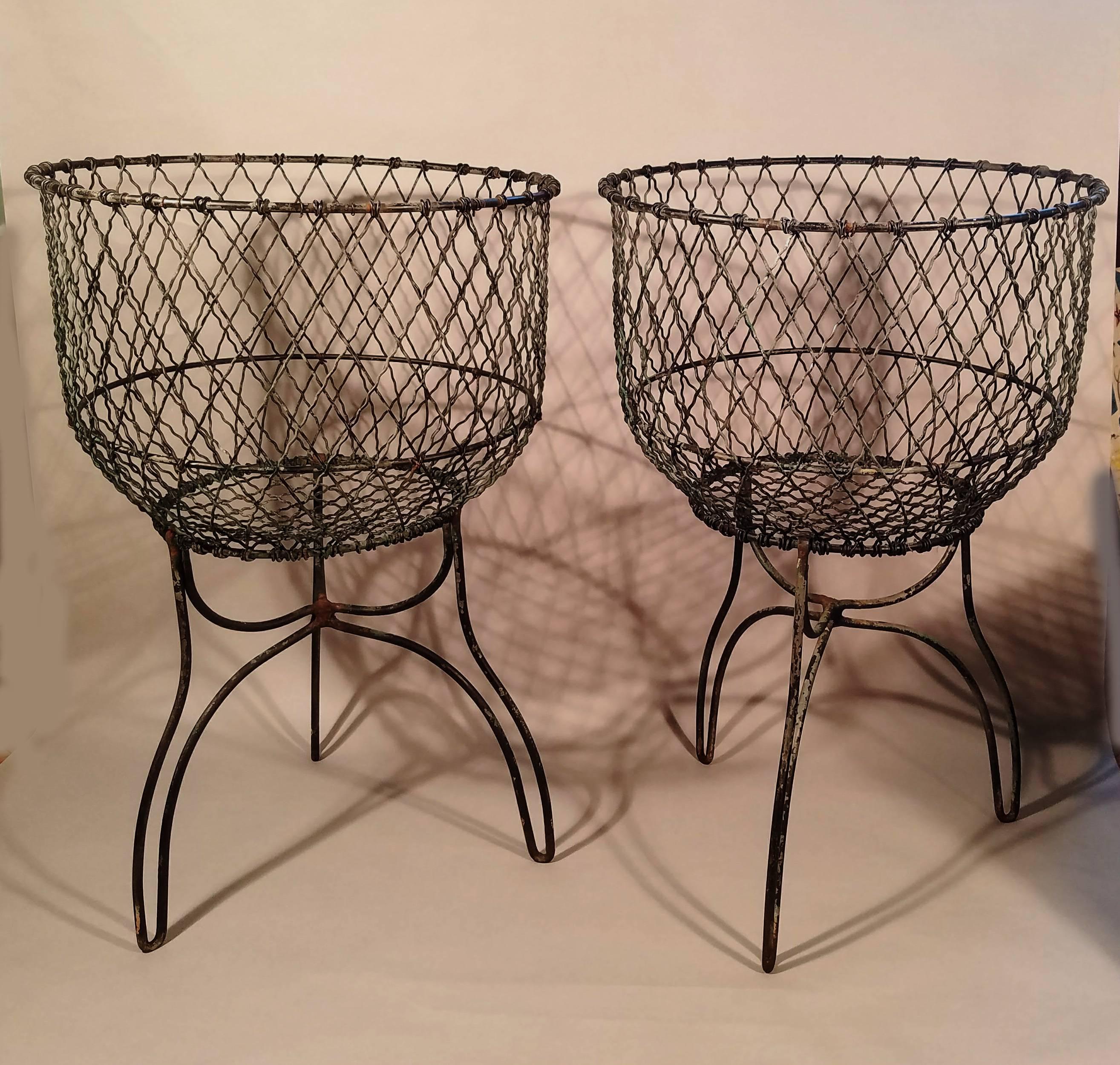 Pair of Antique American Victorian wire baskets
Late 19th-early 20th century.

The pair of baskets came from Sepascot Farm, Rheinbeck. They stand of three hoped feet and the wire is supported by a solid metal band around the neck.

Dimensions: