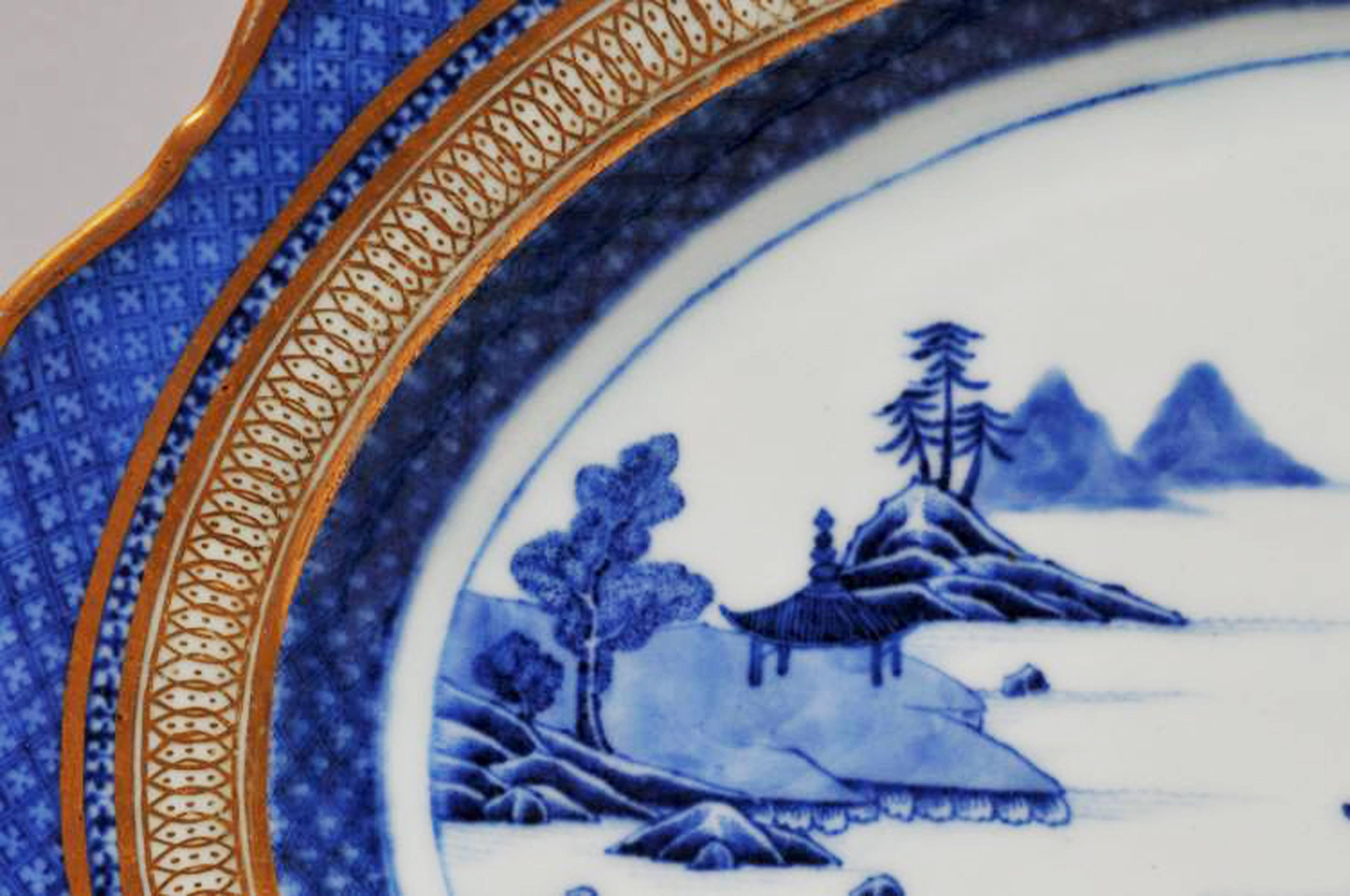 Chinese export porcelain large underglaze blue & white dish with London-decorated gilt border,
circa 1780

A large Chinese Export porcelain scalloped-edged dish with a Hills and Stream pattern with a diaper border and gilt decoration applied in