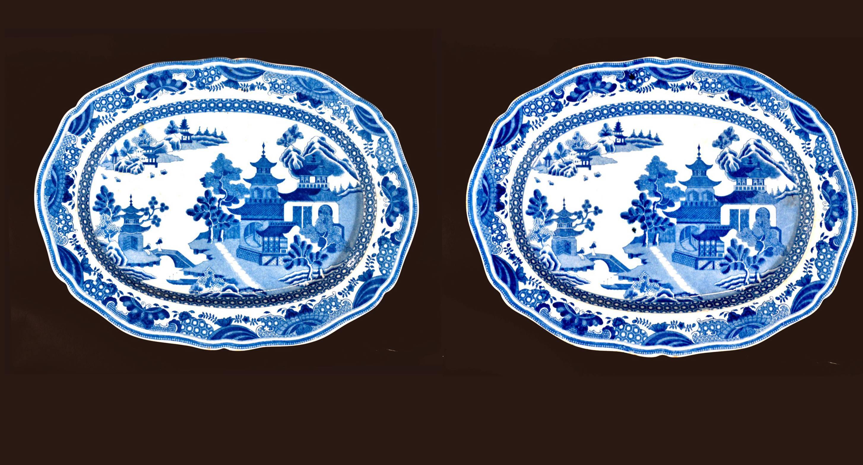 The Pearlware under-glaze blue & white oval dishes are decorated in the central well with a typical Chinoiserie riverscape scene with a pagoda in the forefront and Chinese figures crossing a bridge.
