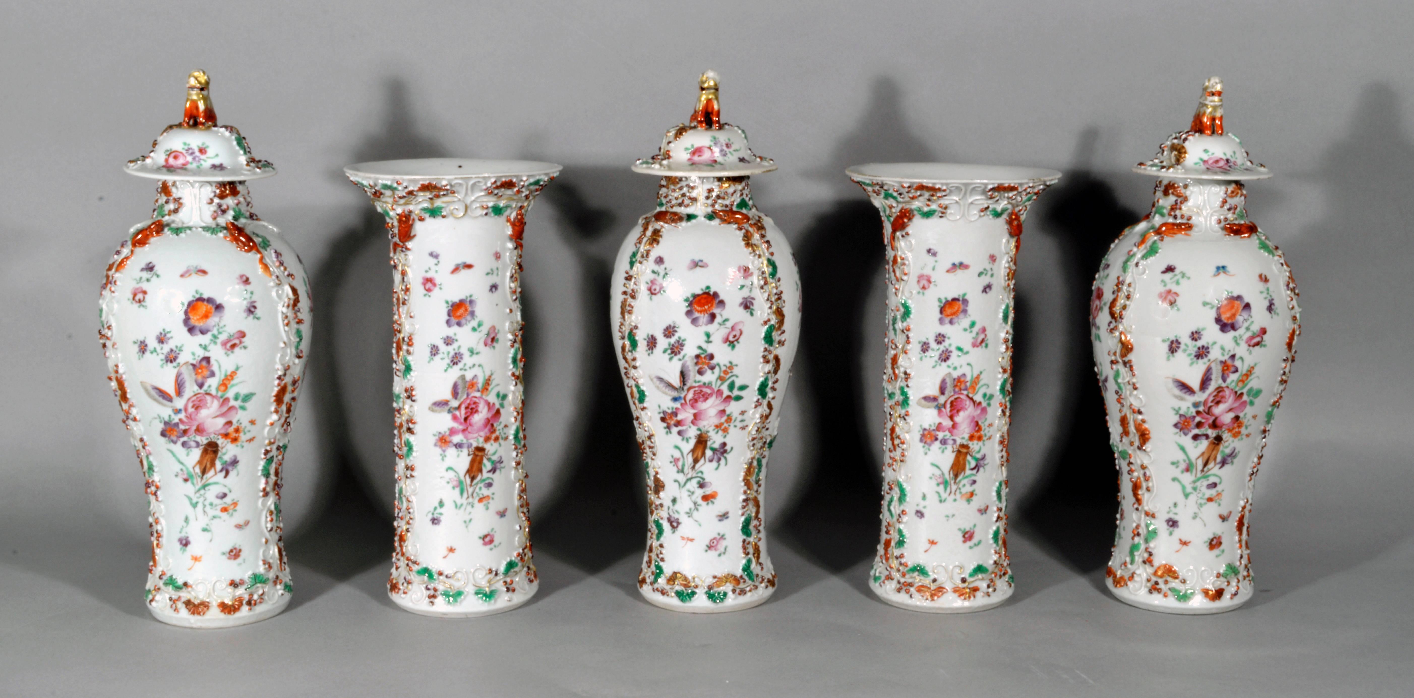 The Chinese porcelain famille rose porcelain garniture is decorated with European flowers, crickets and moths and comprises of five vases, three baluster vases with covers and two of cylindrical trumpet vases with flaring rims, each modeled in low