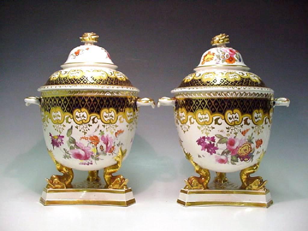 The Ridgway porcelain coolers are decorated in pattern #1173. They have a circular body raised on three dolphin feet and trefoil base and painted with floral sprays under a blue band with gilt lattice decoration. 

Each side has a gilt ring