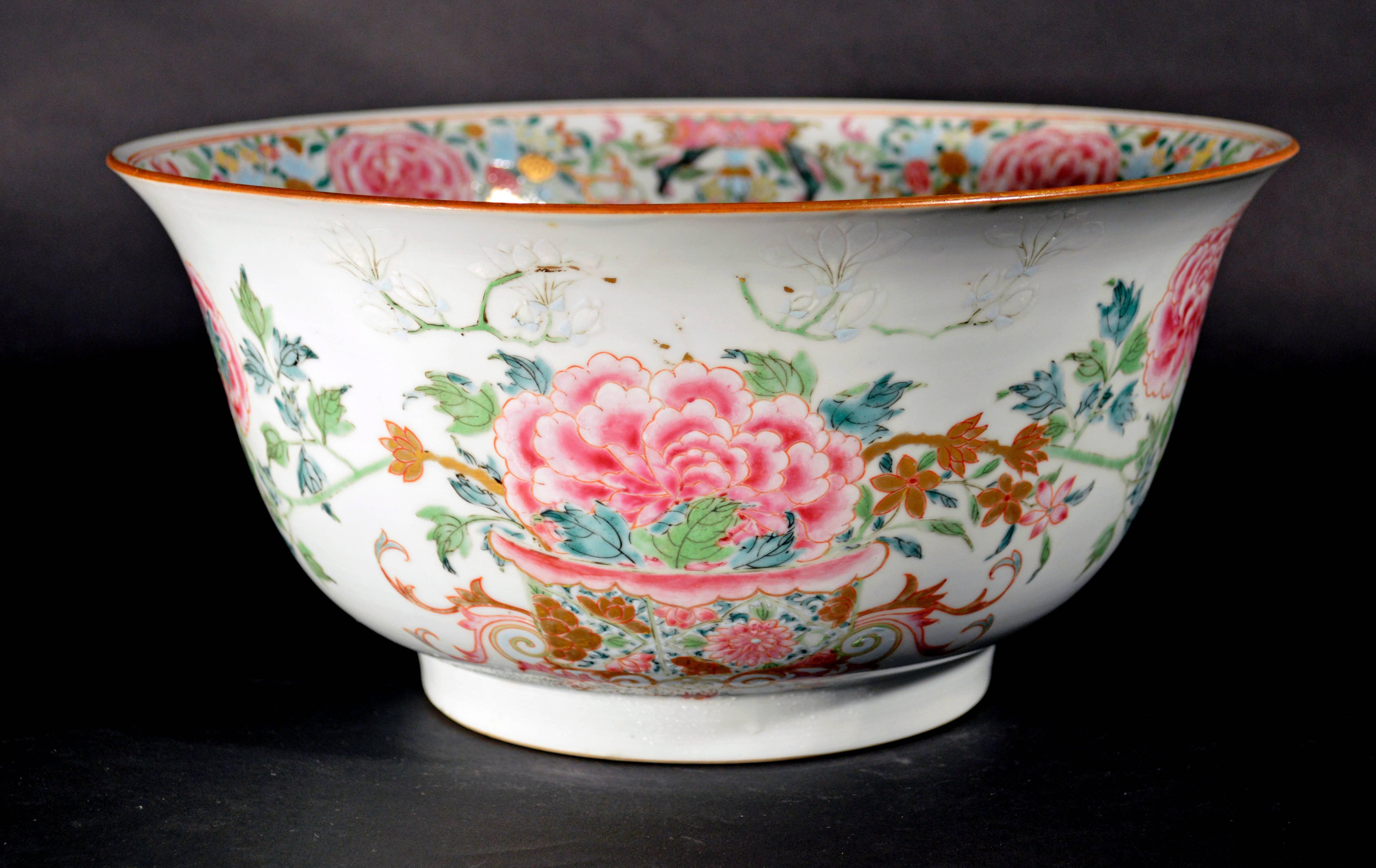 The circular bowl with an unusual flared lip is painted in fine famille rose enamels depicting two images of a large peony flower head in a floral porcelain bowl surrounded by various other flowering plants including jasmine flowers to each side and