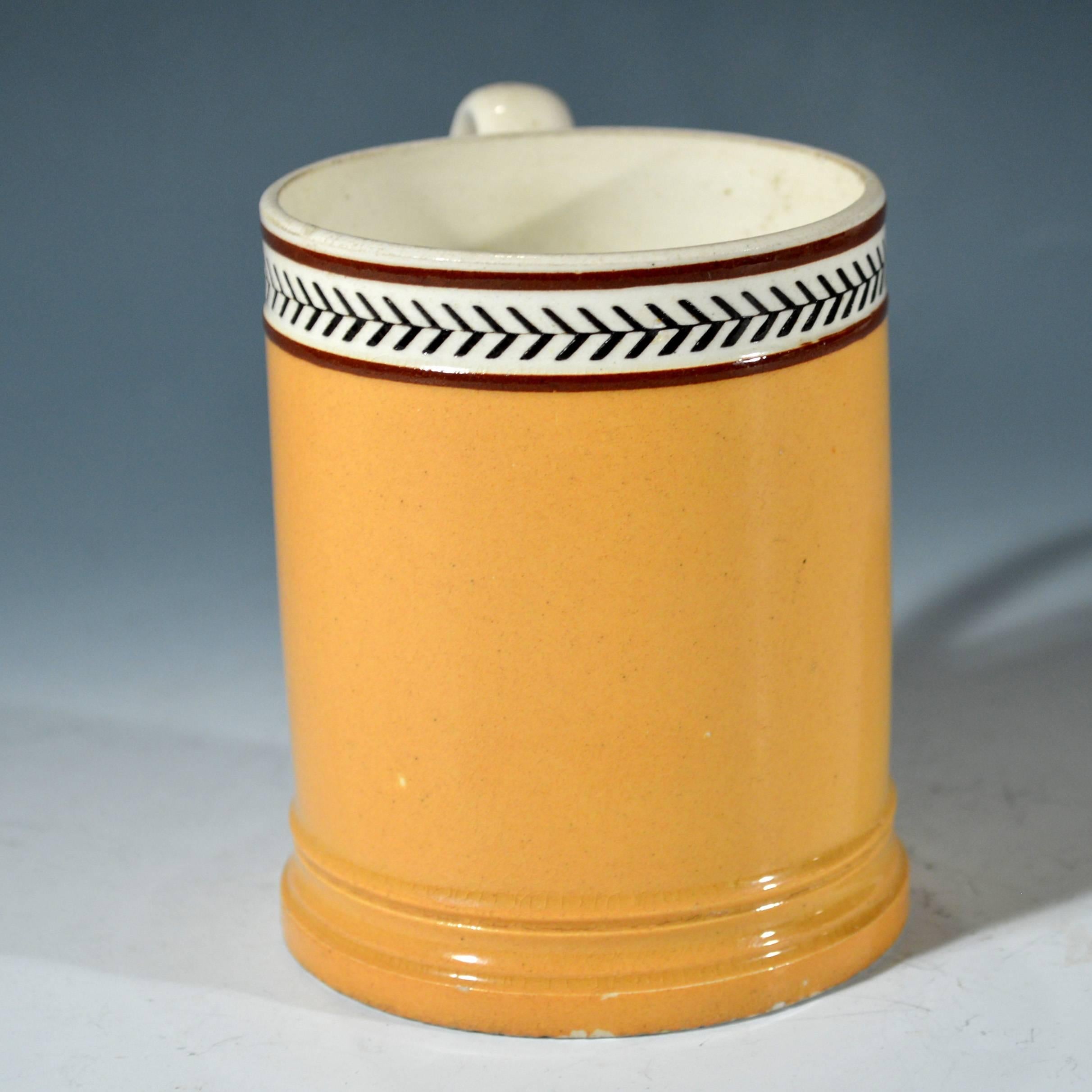 Creamware mocha slip-inlaid rouletted tankard in orange, 
circa 1820.

The creamware mug with C-shaped handle with leaf terminals is slip decorated with an orange-ochre ground and a slip-inlaid rouletted band to the top.

Dimensions: Height 3