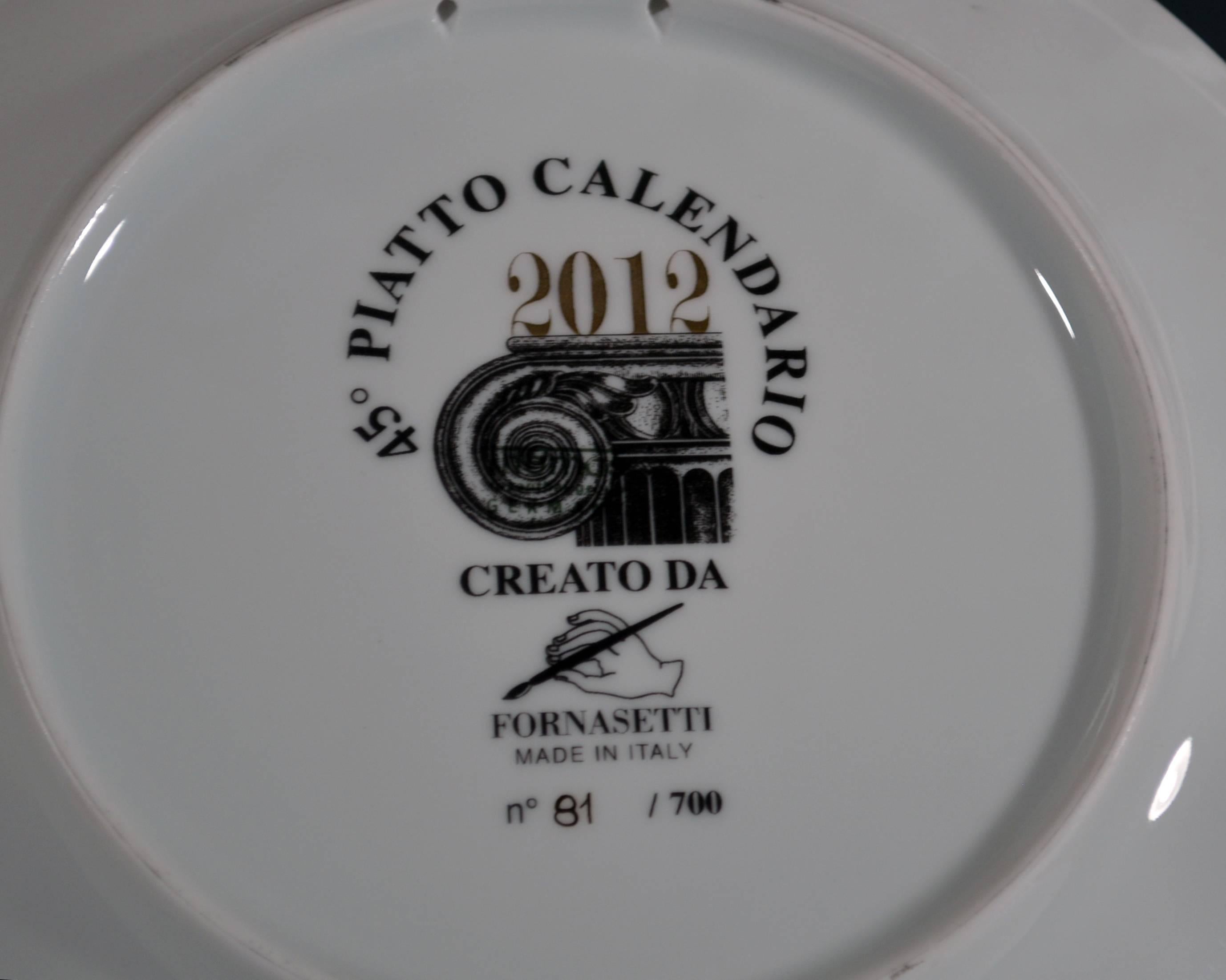 Fornasetti Calendar Plate for 2012, 
Barnaba Fornasetti,
No. 81of 700.

The plate depicts a cupid blowing cards with the days of the months forward with a Grecian Architectural column on the other side of the plate, with the date 2012 and the