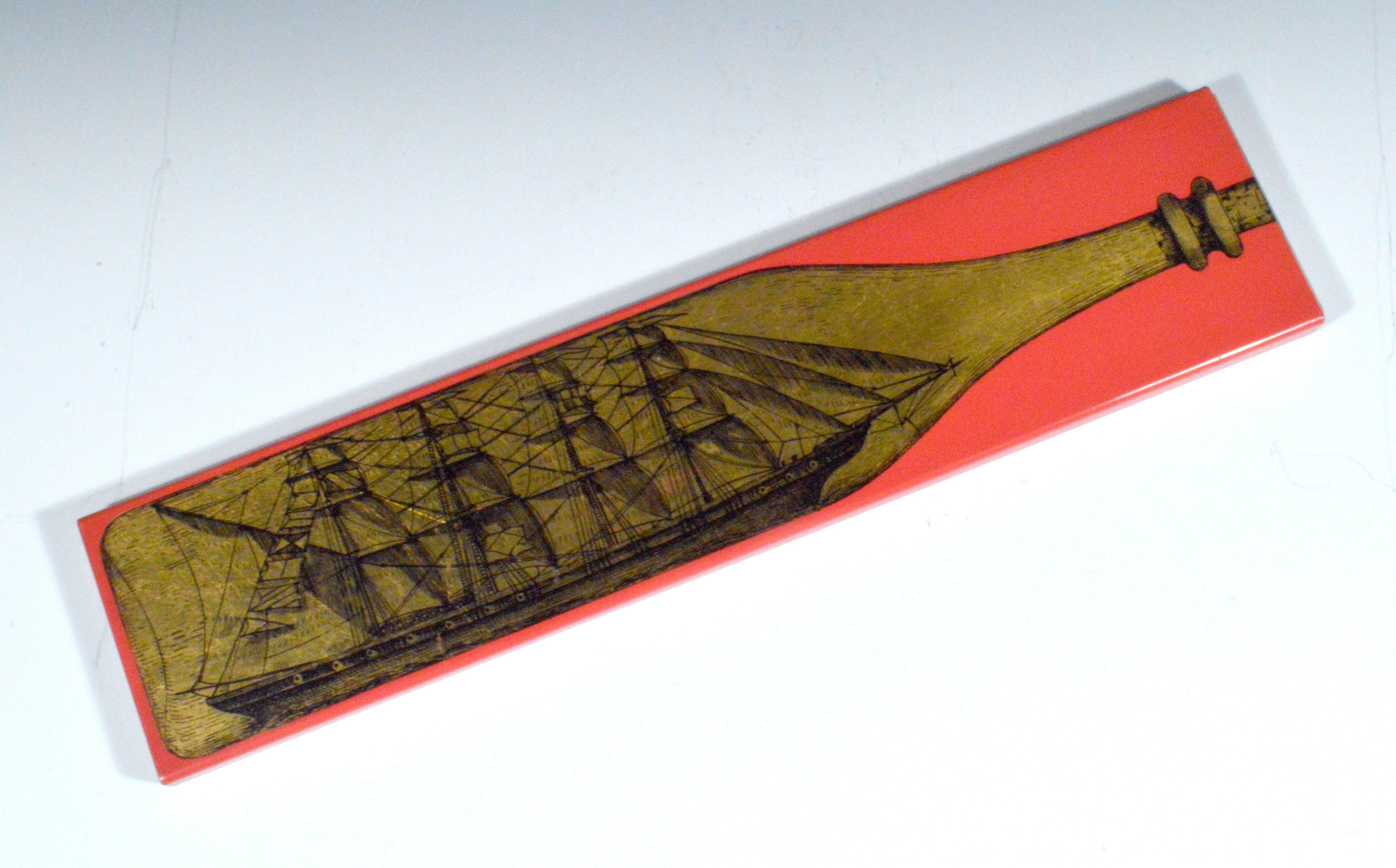 Vintage Piero Fornasetti long cigarette box with ship in a bottle design,
Bottiglia (Bottle),
1960s.

The Piero Fornasetti ship in a bottle design metal box has a red ground. There is a red felt base stamped in gold with the Fornasetti