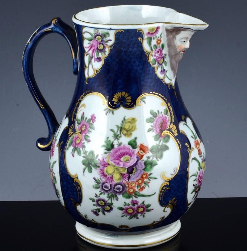An unusual first period worcester porcelain blue scale ground mask jug with multiple panels with botanical decoration, circa 1775.

Mark: Underglaze blue square fret mark.



        