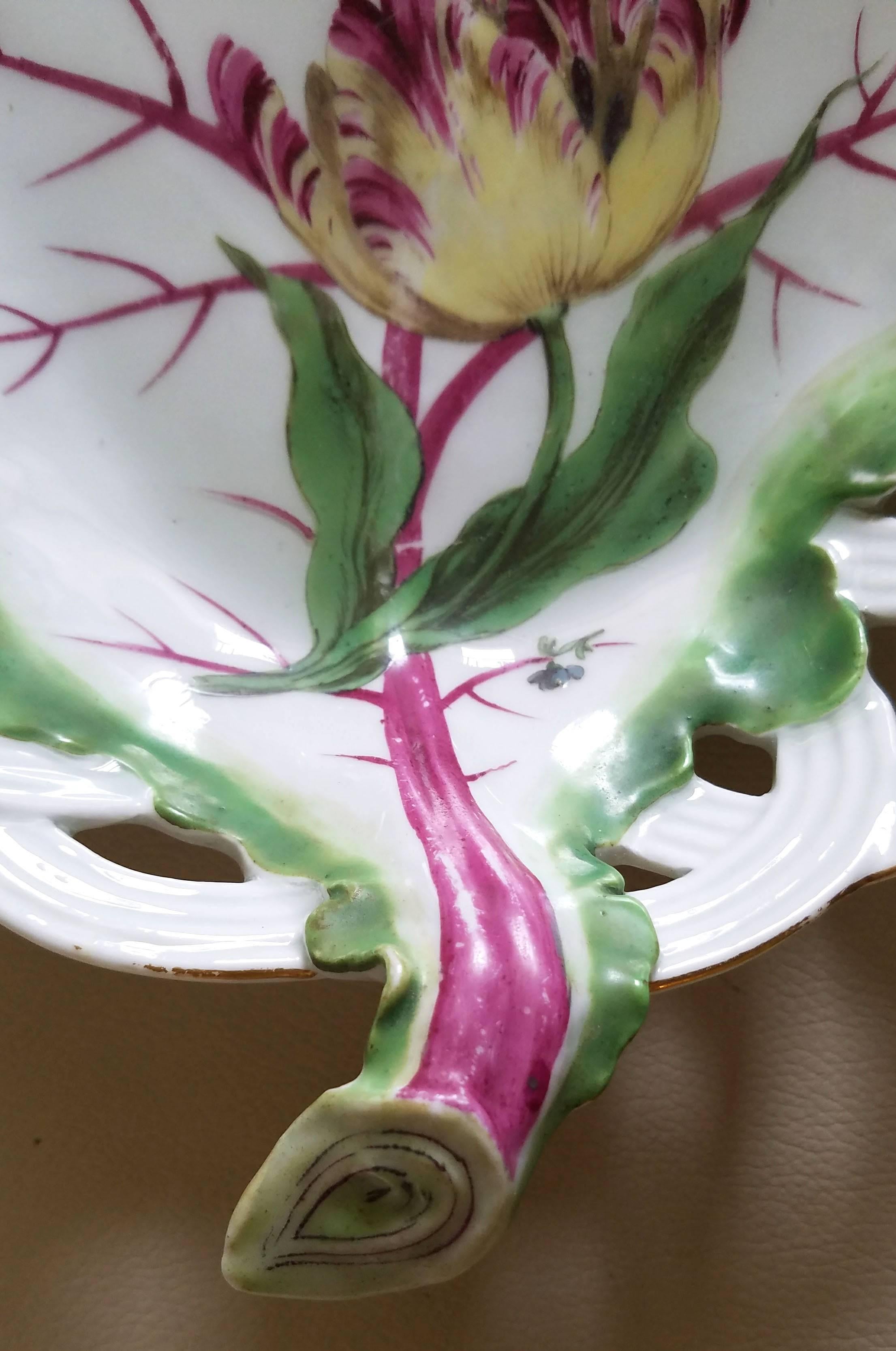 Chelsea porcelain pair of tromp l'oeil leaf dishes with tulips,
circa 1765-1770.

The pair of tromp l'oeil porcelain Chelsea Porcelain dishes each depict a large green leaf with purple veining lying on an openwork basket and each painted with a