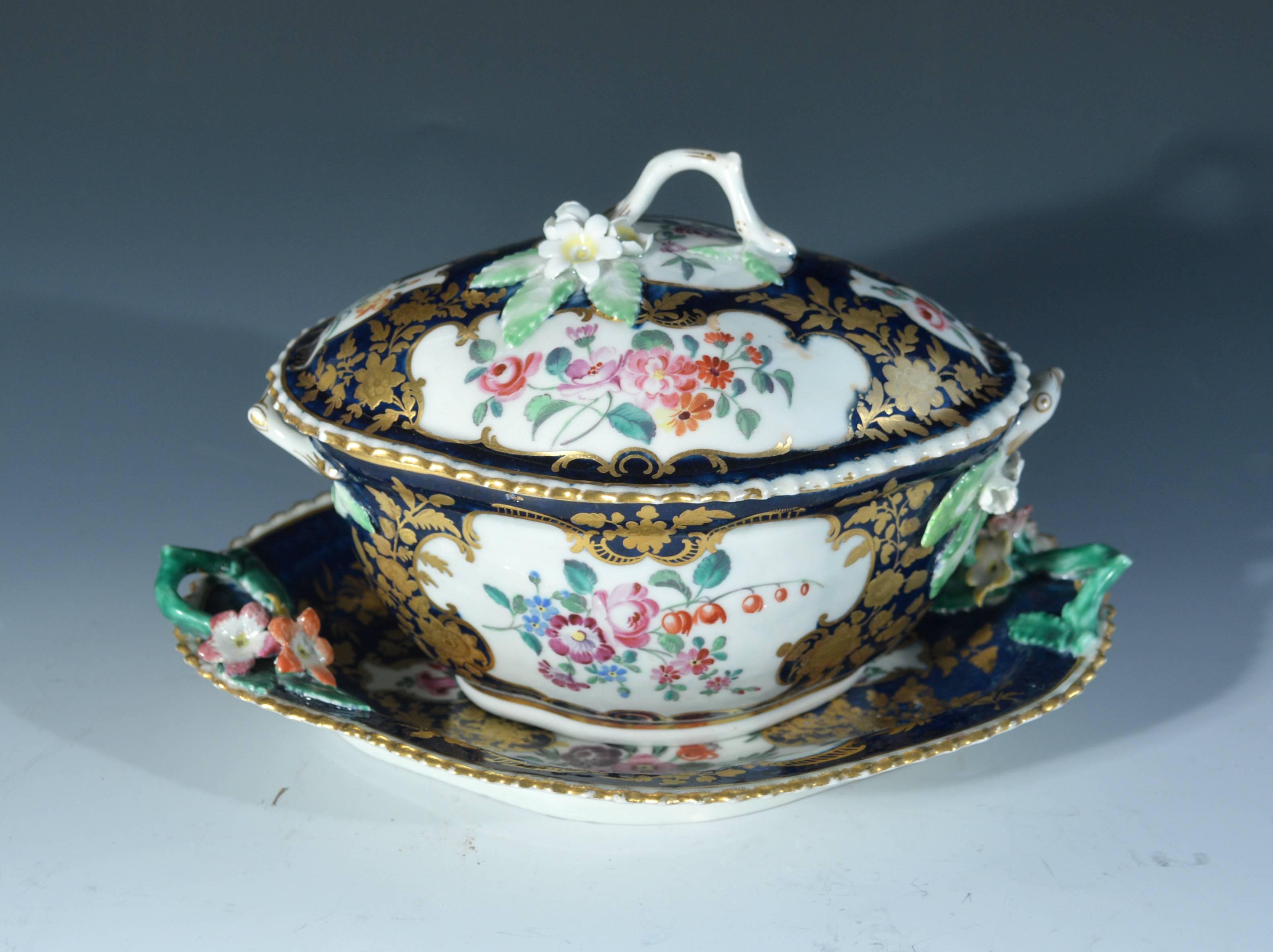 First period Worcester porcelain mazarine blue-ground botanical sauce tureen cover & stand,
circa 1765-1775.

The oval tureen, cover and stand with mazarine blue ground highlighted with panels of flowers and the handles in the form of flowering