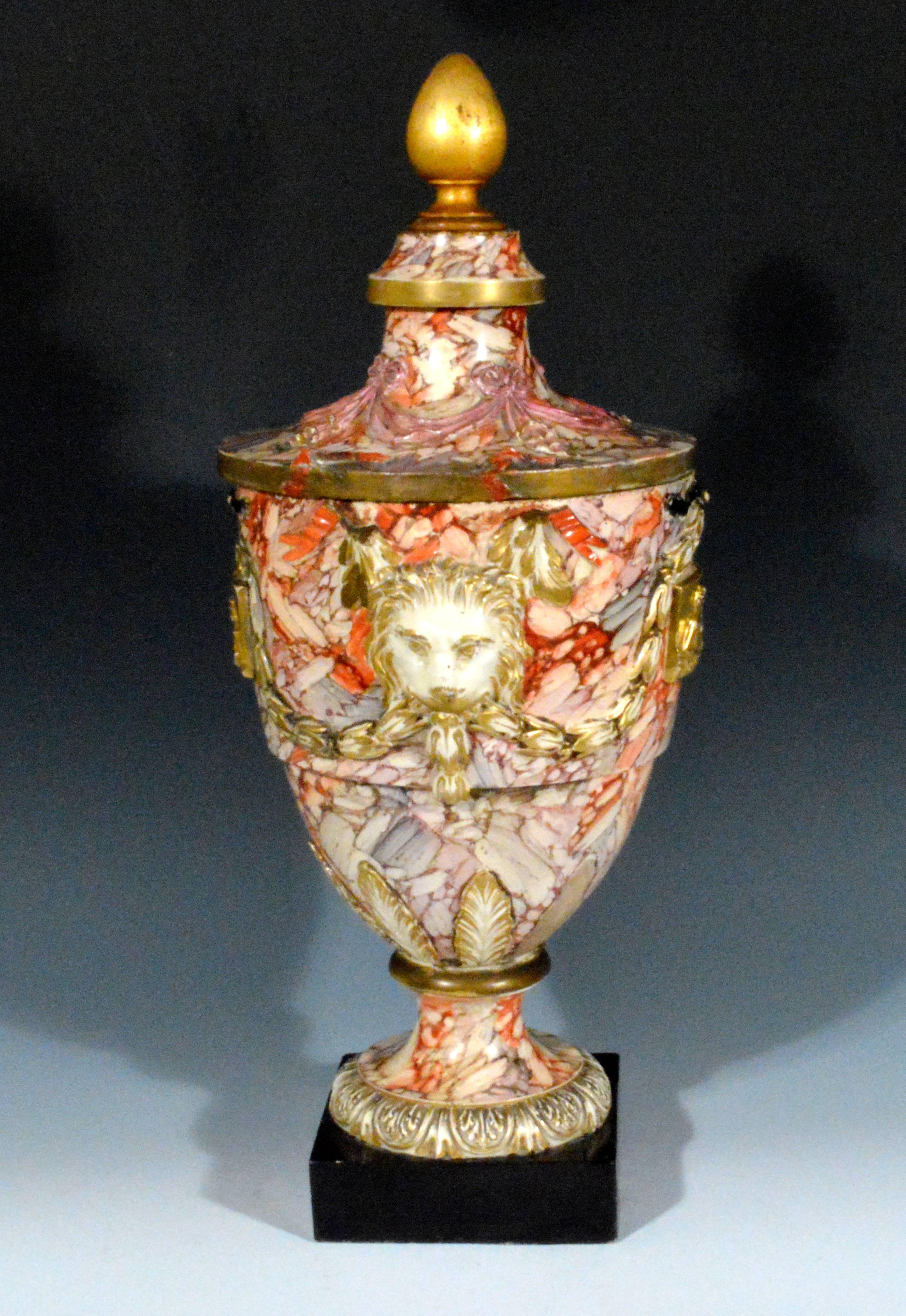 Continental large marbled pottery urn or vase, Baltic region, circa 1790.

The urn painted in a marbled design has a narrow foot sitting on a square black pottery base rising to a circular body with applied lion-head masks highlighted in gilt to