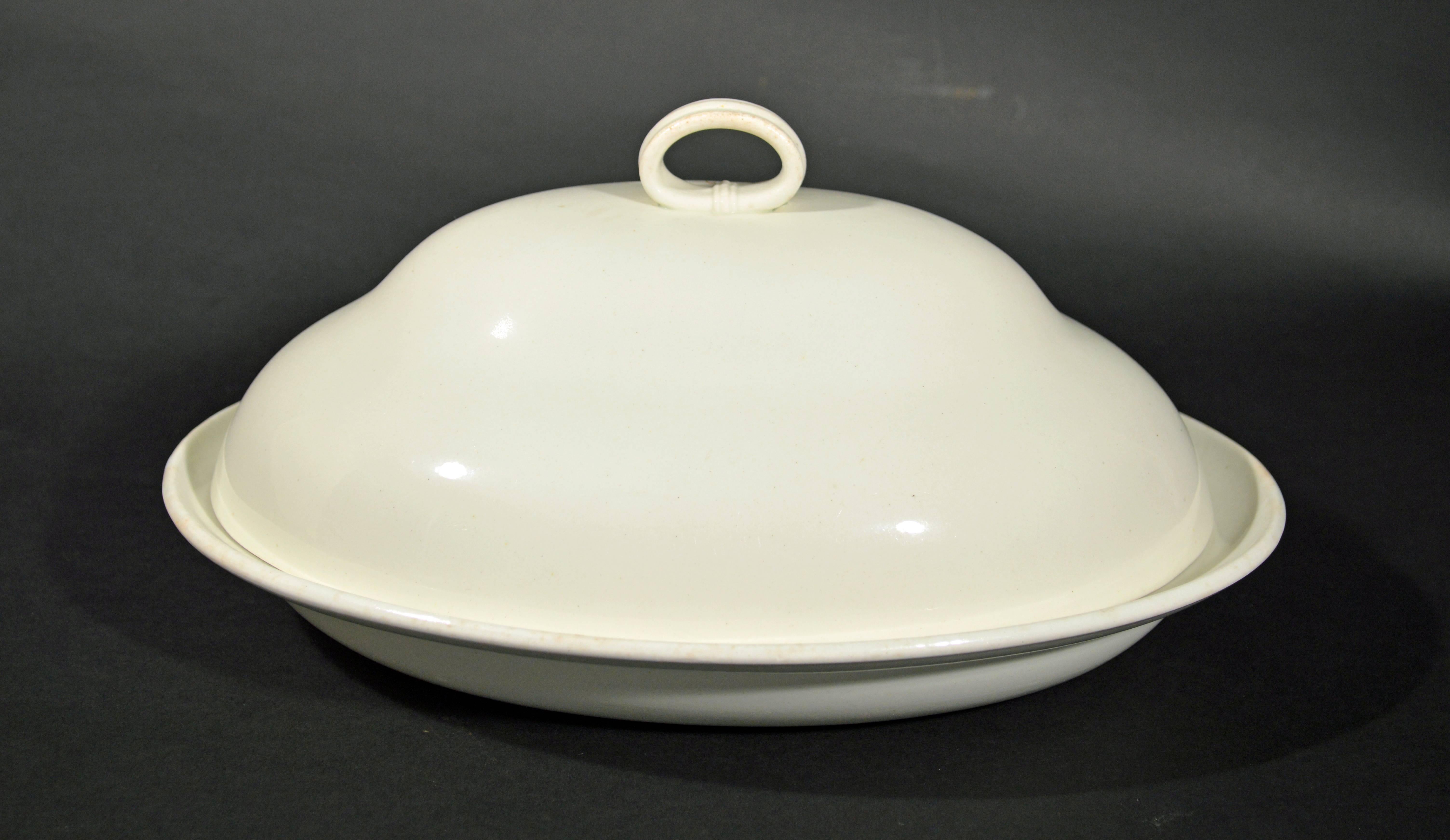 Wedgwood plain creamware vegetable tureen and cover,
circa 1785-1800.

Neoclassical wedgwood vegetable tureen and cover consists of a shallow oval body with an angled rim with a double domed cover surmounted with a simple double ribbed oval strap